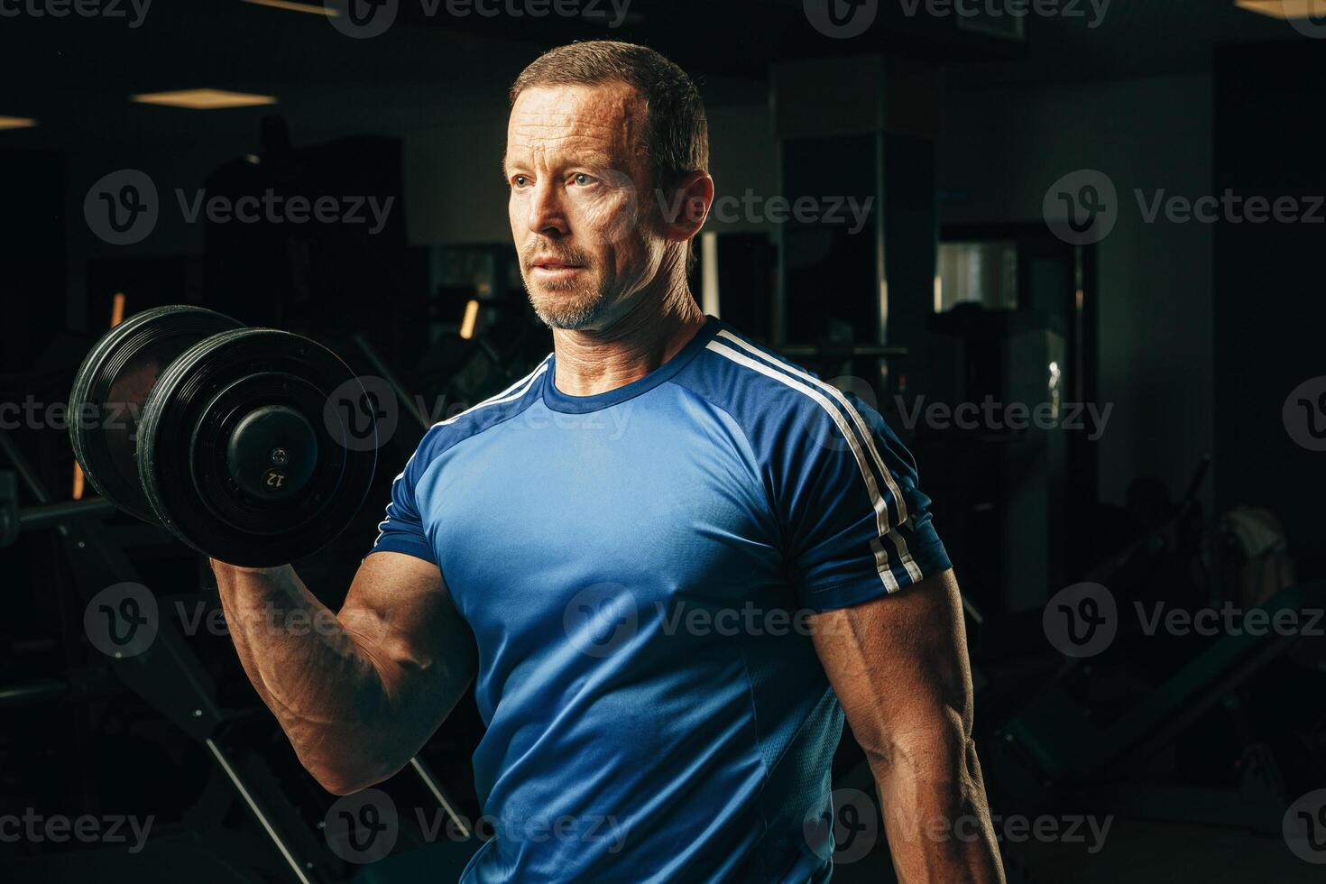 Fit senior man exercising with dumbbells in a gym photo