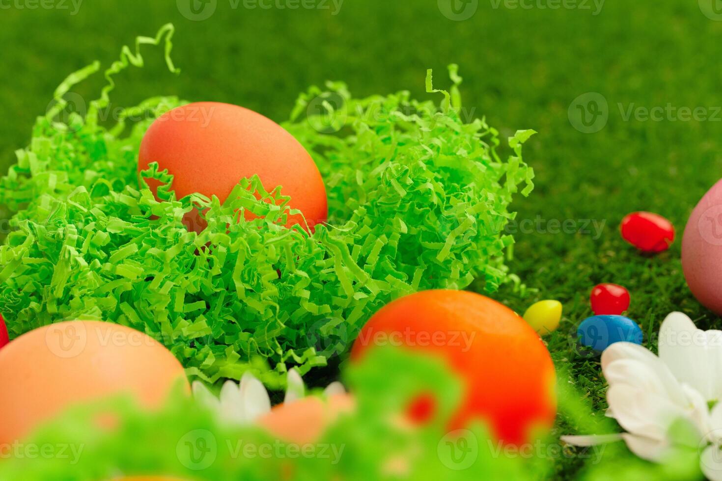 Close up photo of colored Easter eggs and candies on grass
