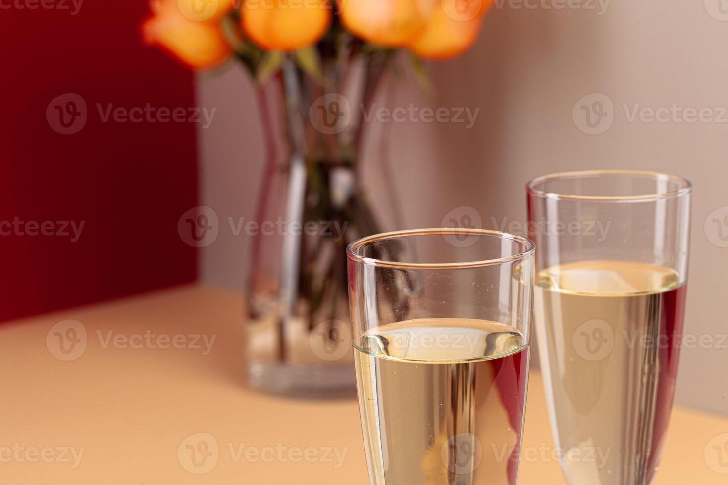 Close up photo of champagne glasses with roses in a vase