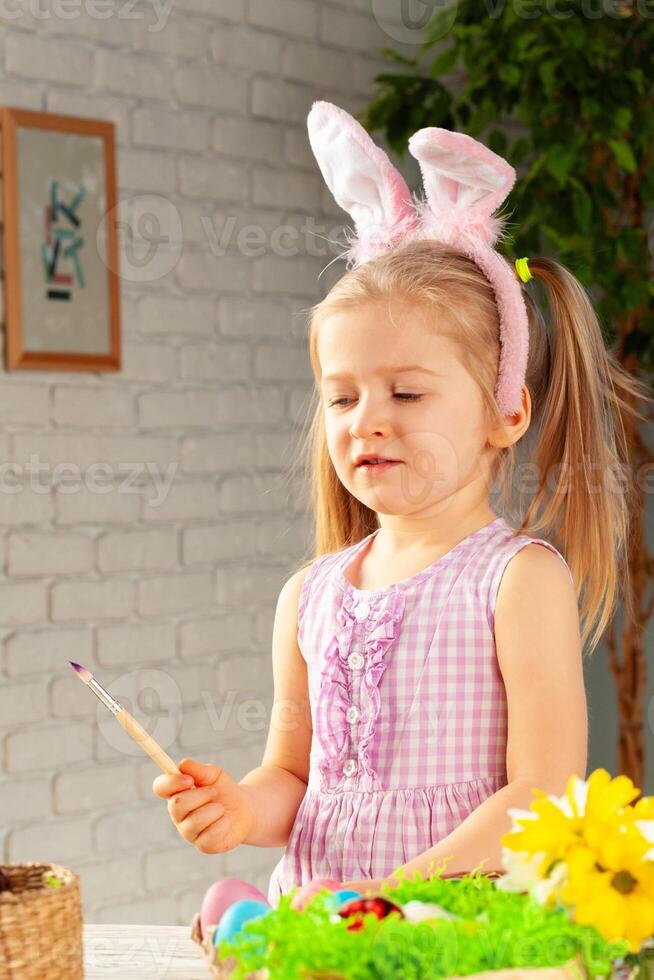 Portrait of a cute girl with paintbrush ready to paint eggs photo