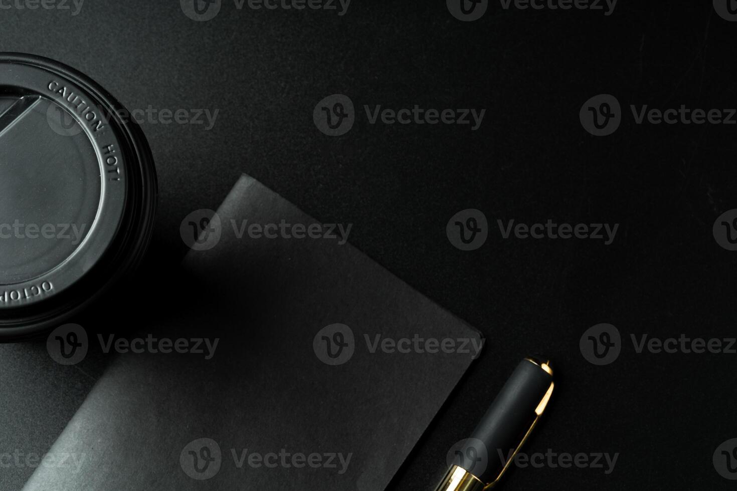 Black notepad with pen on black table close up photo