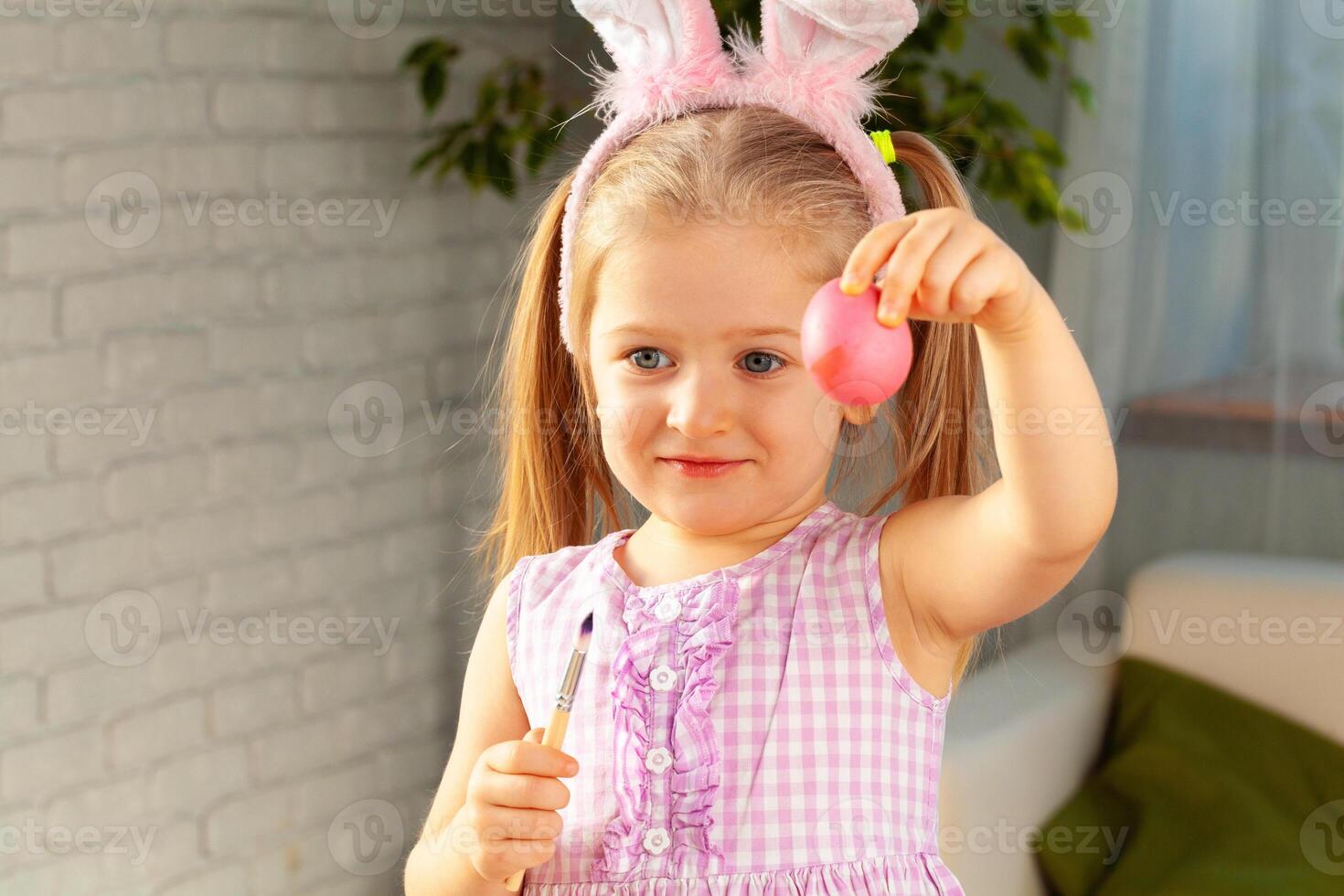 Happy little girl just painted an egg for Easter photo