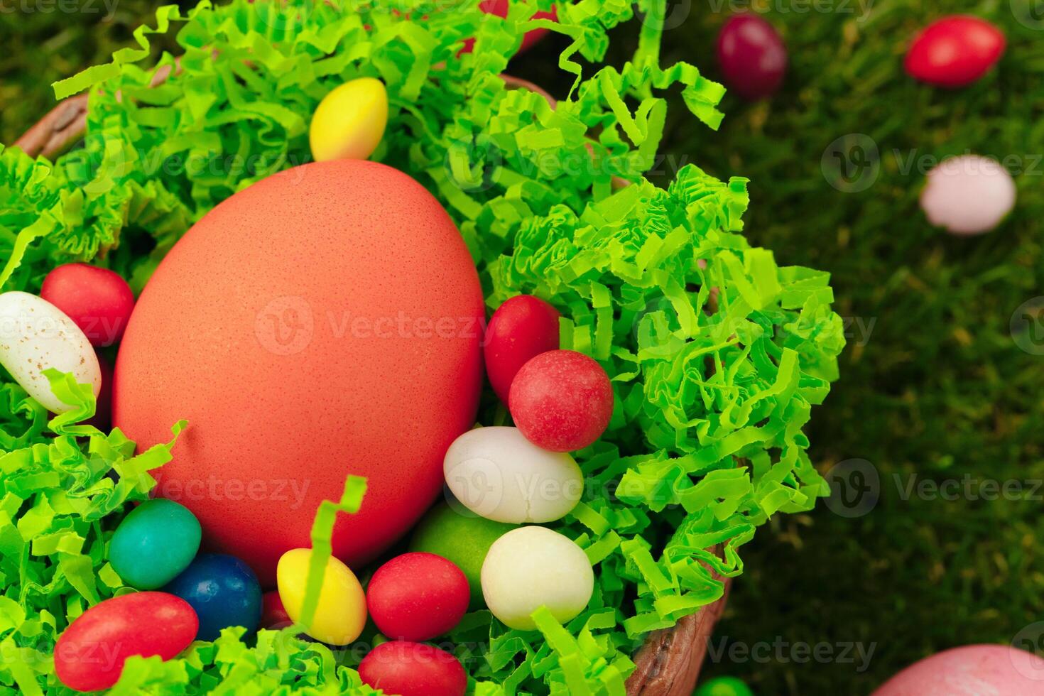 Close up photo of colored Easter eggs and candies on grass