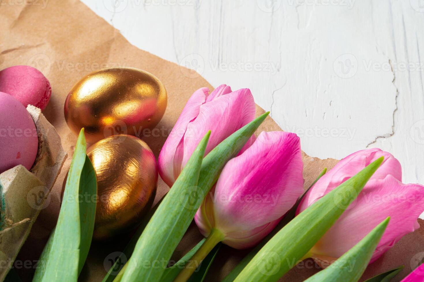 Painted Easter eggs in an eggbox with fresh tulips close up photo