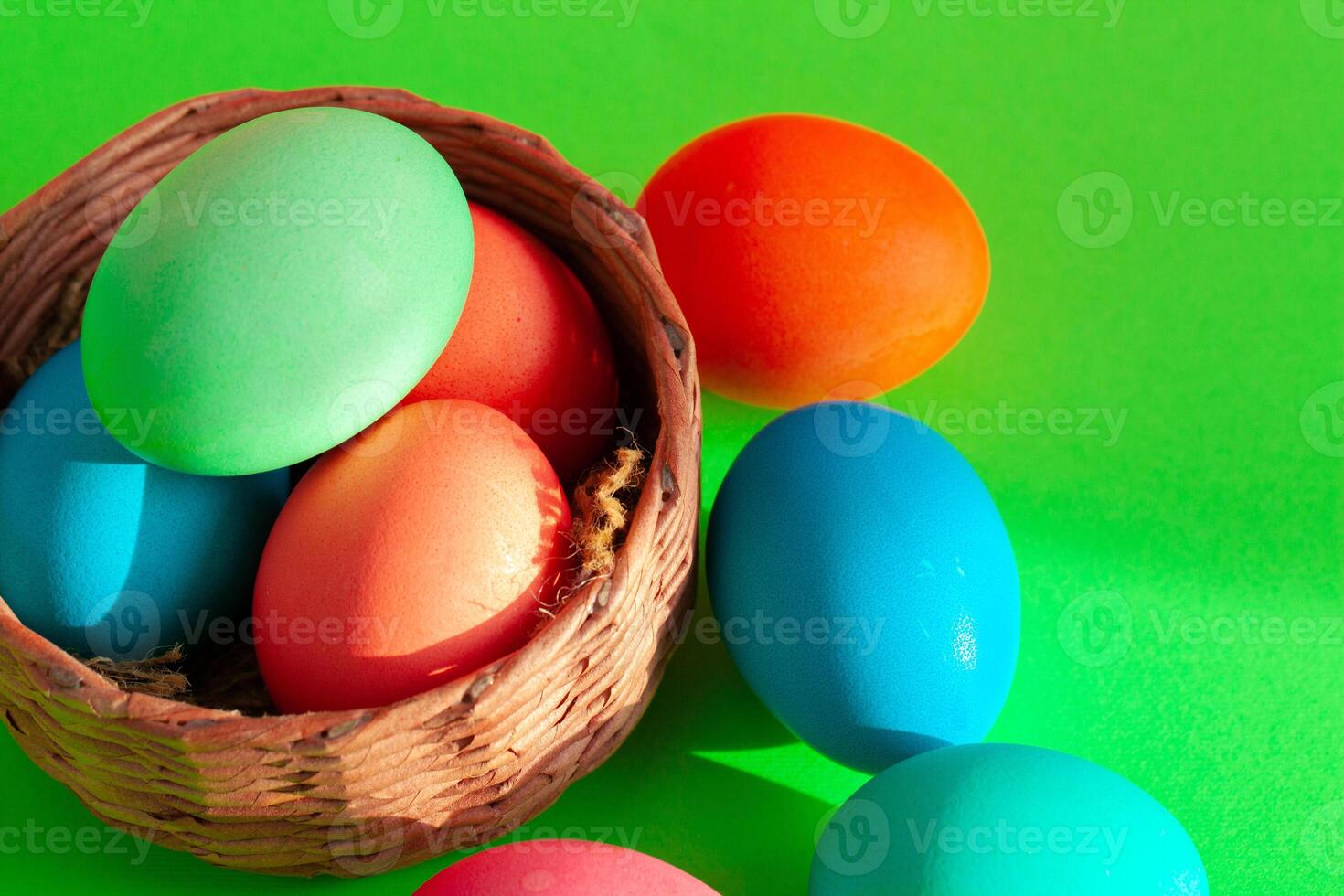 Vibrant colored eggs in a nest on green. Easter concept photo