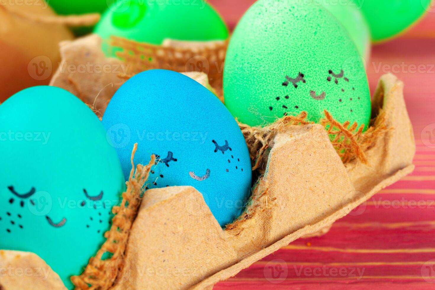 Blue and green colored Easter eggs with drawn funny faces photo