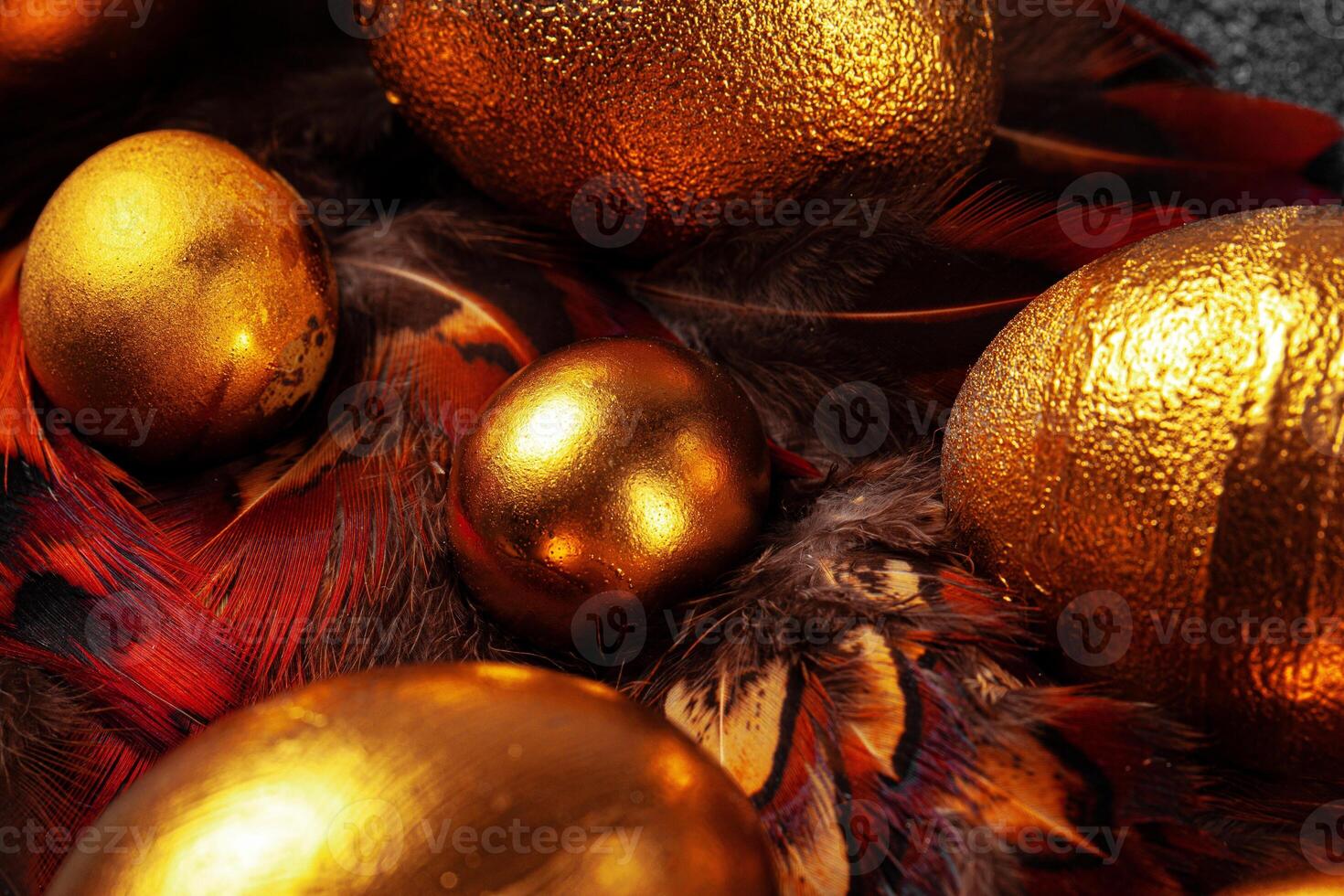 Golden Easter eggs on red bird feathers close up photo
