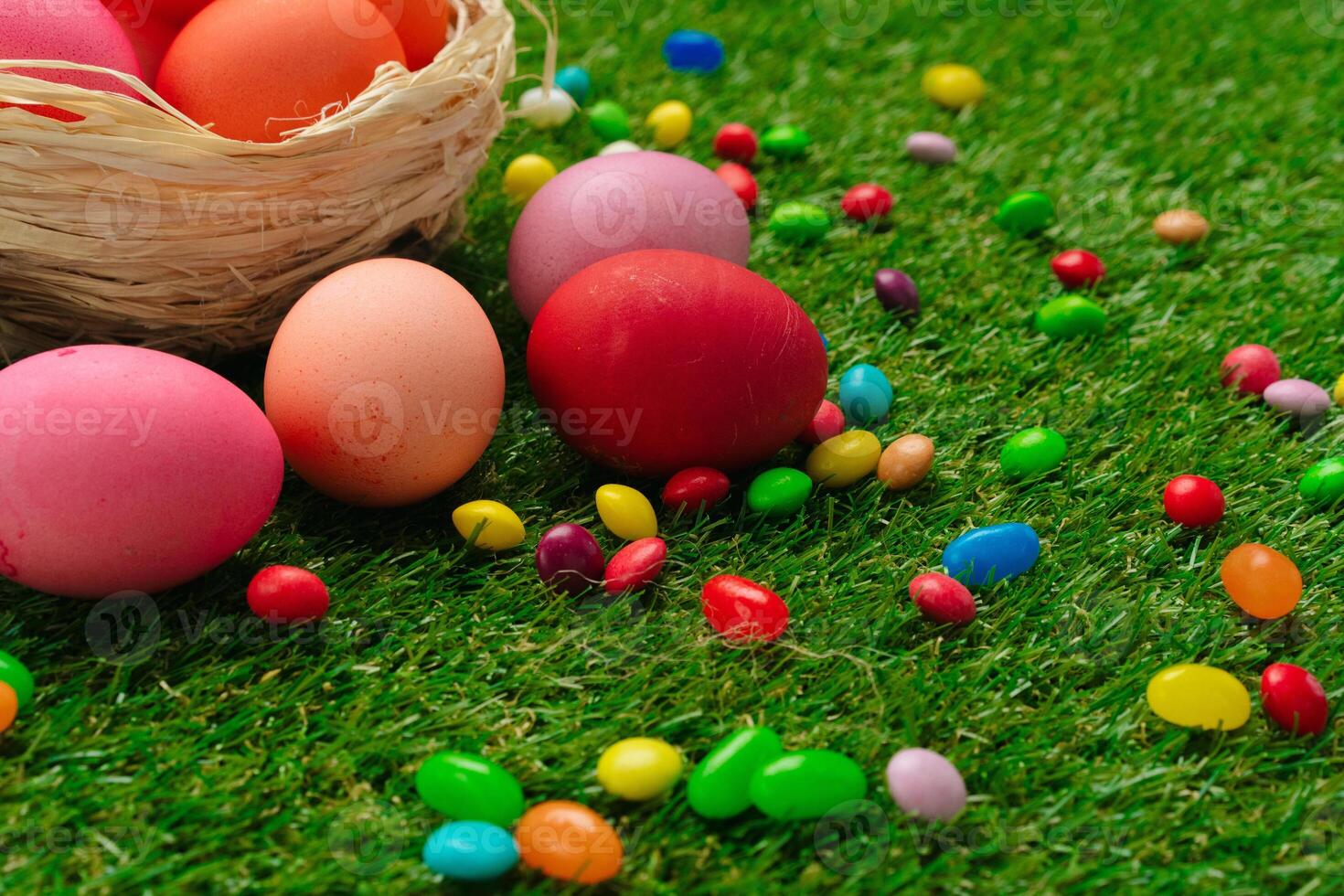 Colored eggs and vibrant candies on grass. Easter composition photo