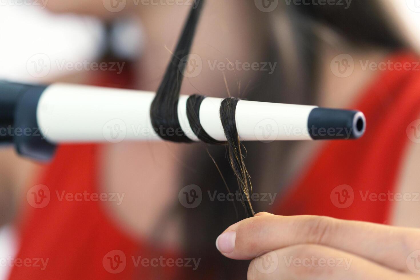Hairstylist curling hair client in hairdressing salon photo