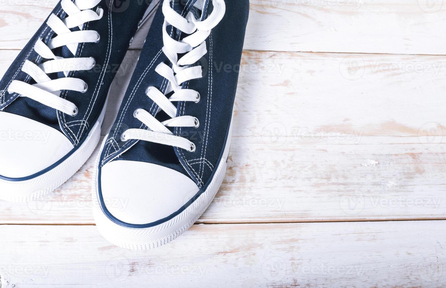 Youth classic gumshoes with white the laces on wooden background photo