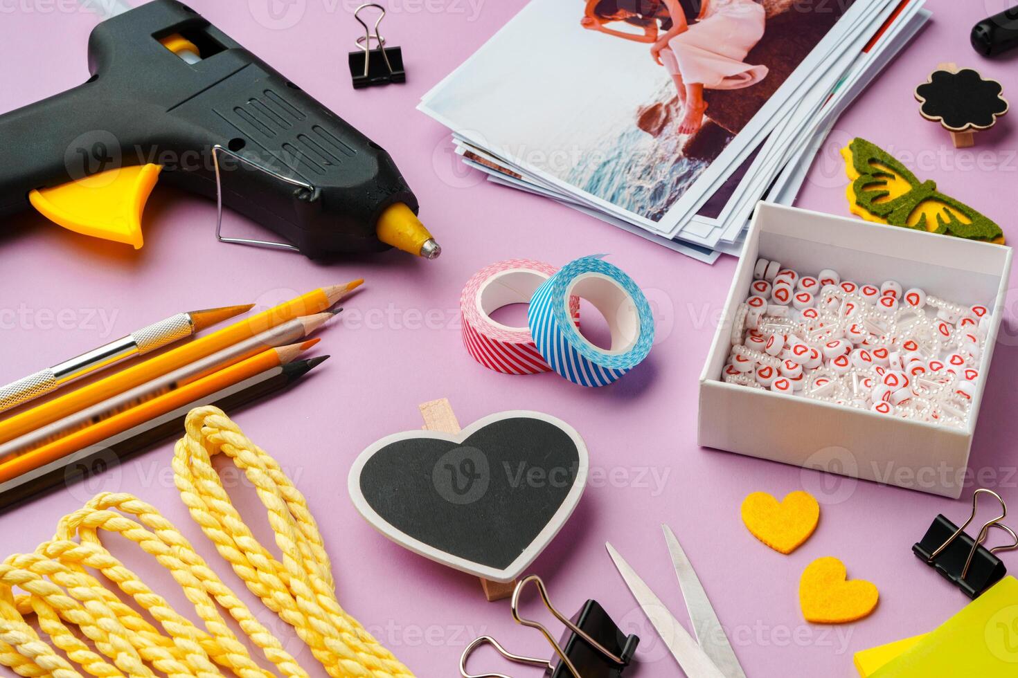 Crafting supplies arranged on a pink background, including glue gun, scissors, and decorative items for DIY projects photo