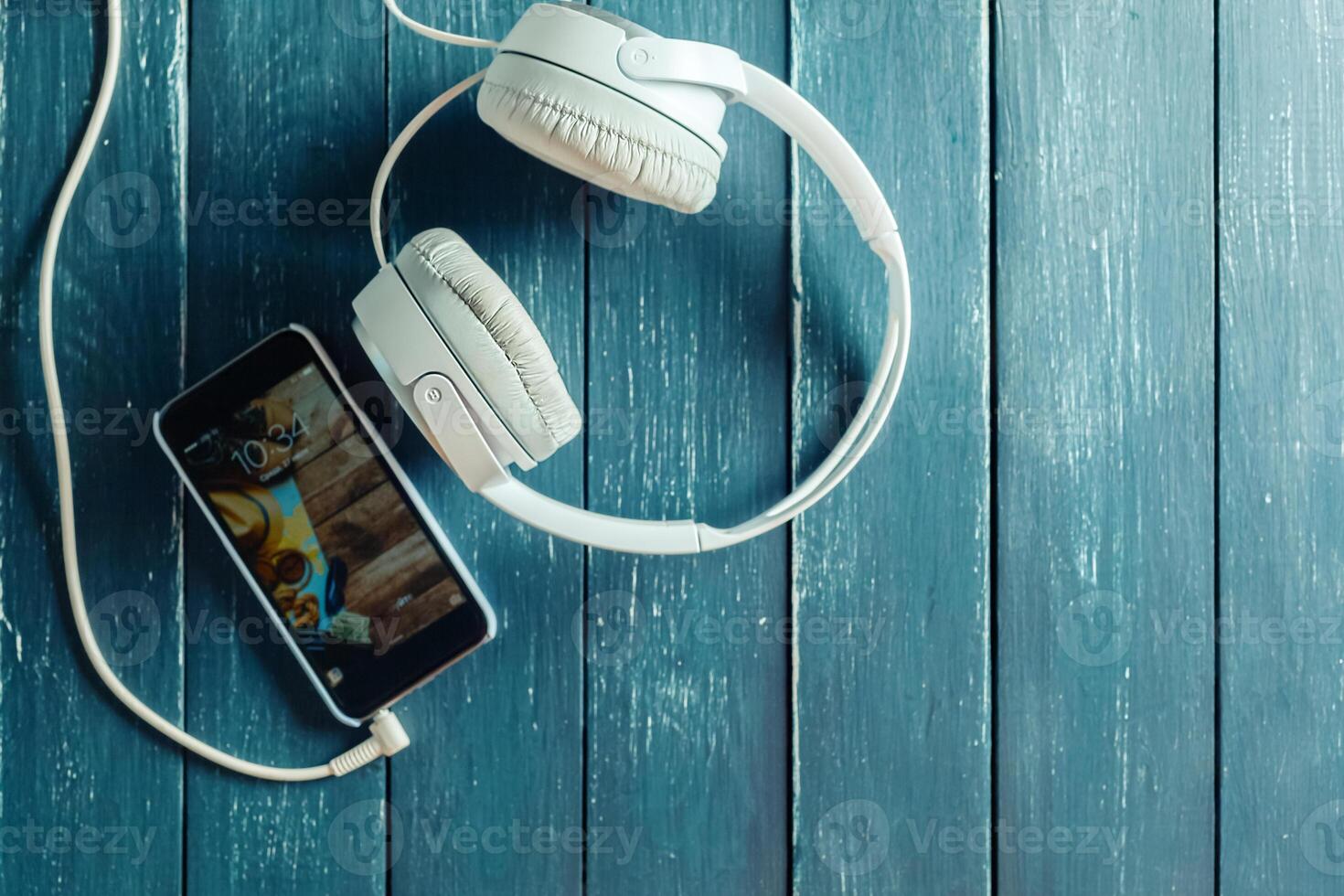 white earphones attached to smartphone on wooden background photo
