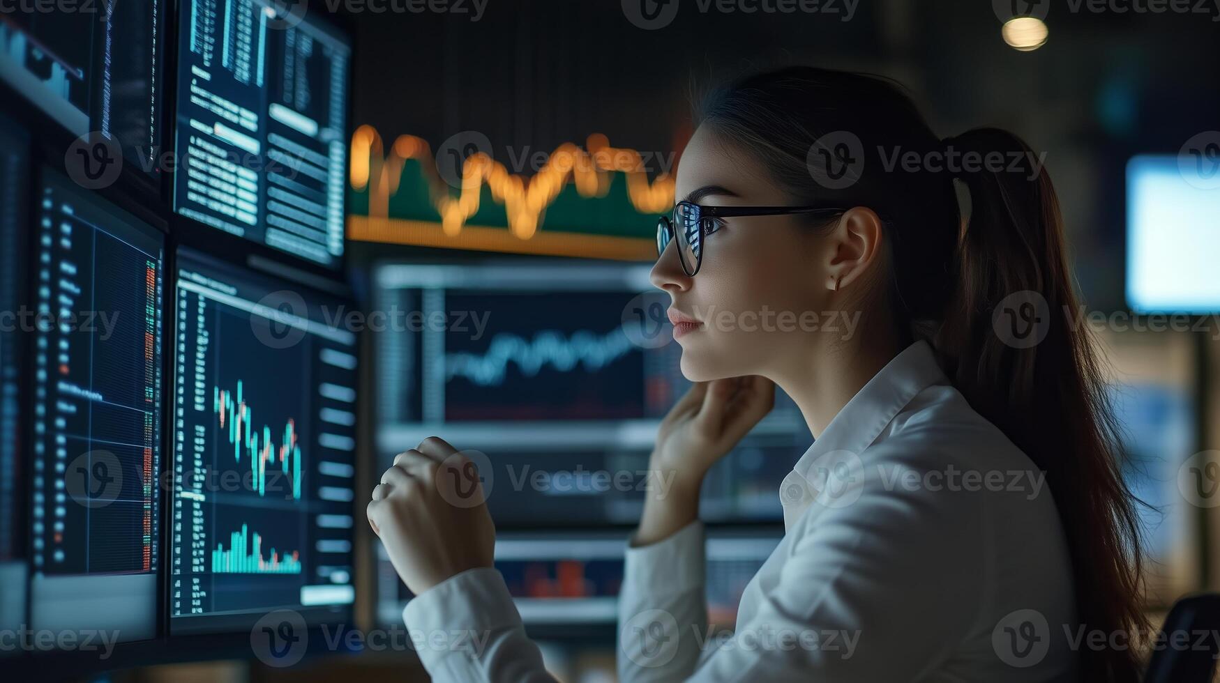 Professional woman analyzing financial data on multiple screens at a modern office during evening hours photo
