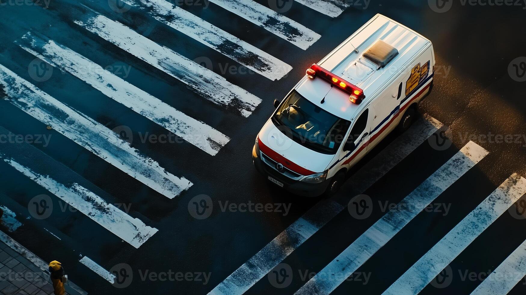 An ambulance crosses a wet crosswalk, responding to an emergency call during early morning hours in an urban setting photo
