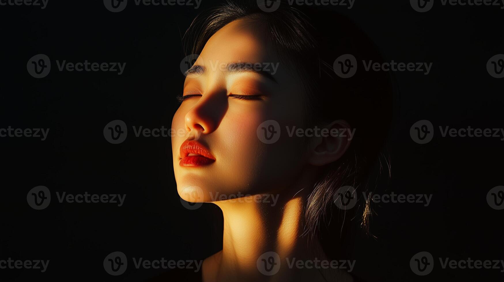 A woman with closed eyes enjoying warm sunlight streaming in on her face during a serene moment in a dimly lit room photo