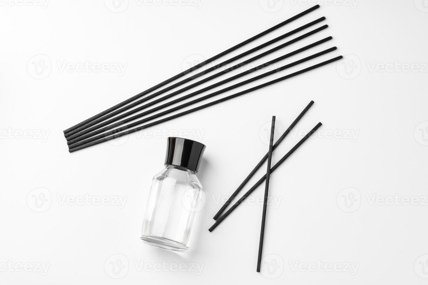 A minimalist display of essential oil and black diffuser sticks on a clean white background photo