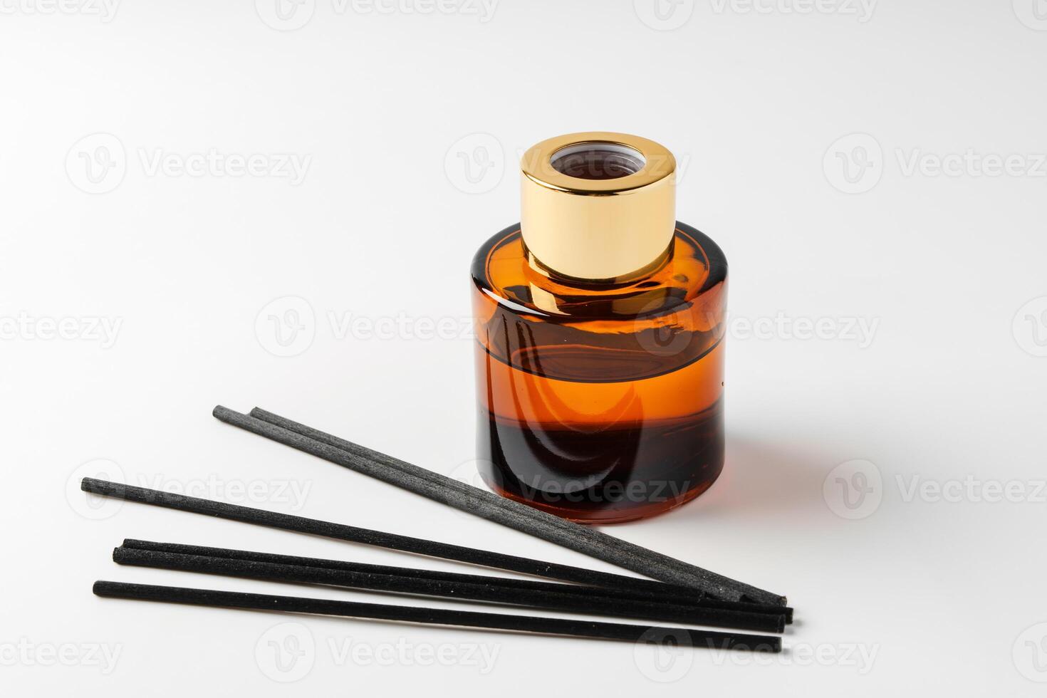A minimalist display of essential oil and black diffuser sticks on a clean white background photo