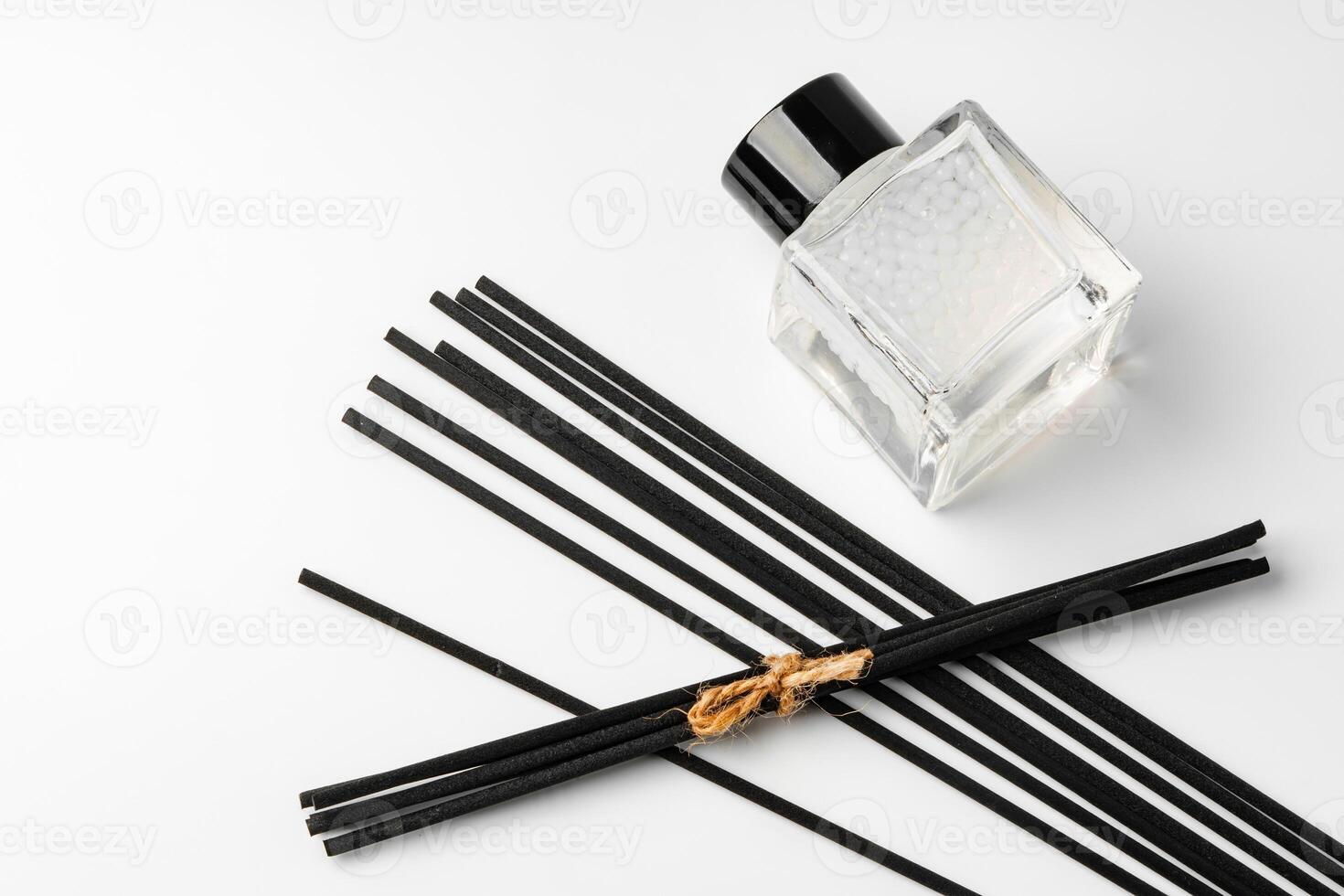 A minimalist display of essential oil and black diffuser sticks on a clean white background photo