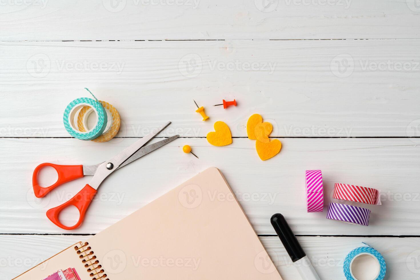 Creative workspace with open notebook, stationery, and decorative items on a wooden table photo