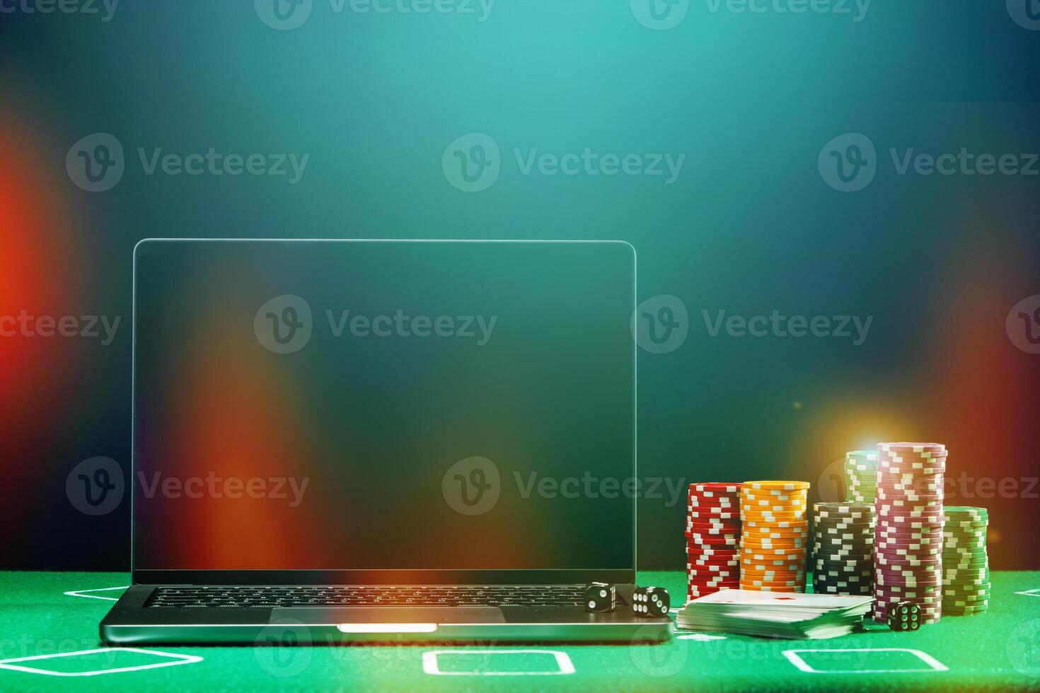 A laptop and poker chips arranged on a green felt table in an indoor gaming setup during a nighttime gambling session photo