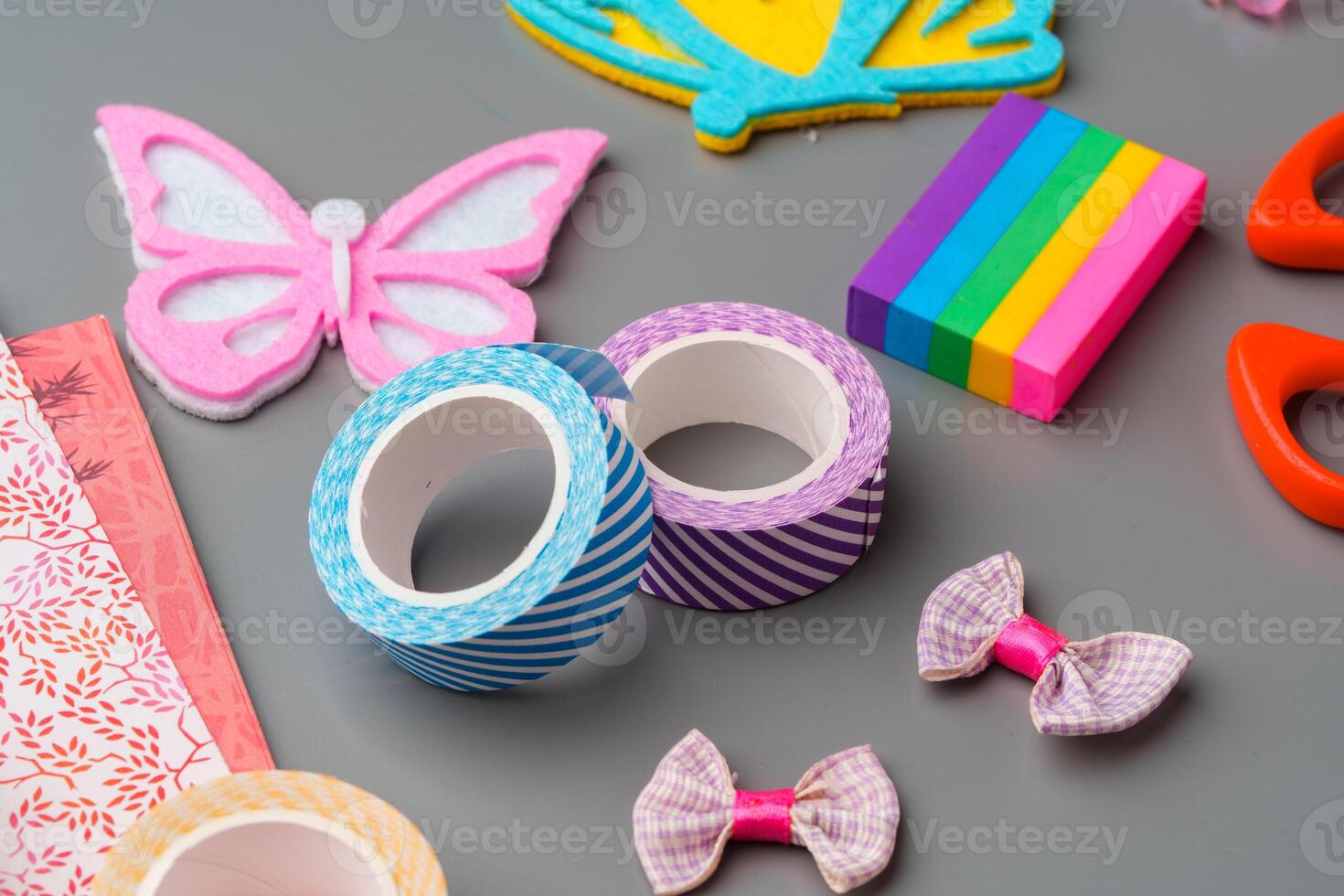 Crafting supplies arranged for a DIY project on a gray table with scissors, washi tape, and decorative items photo