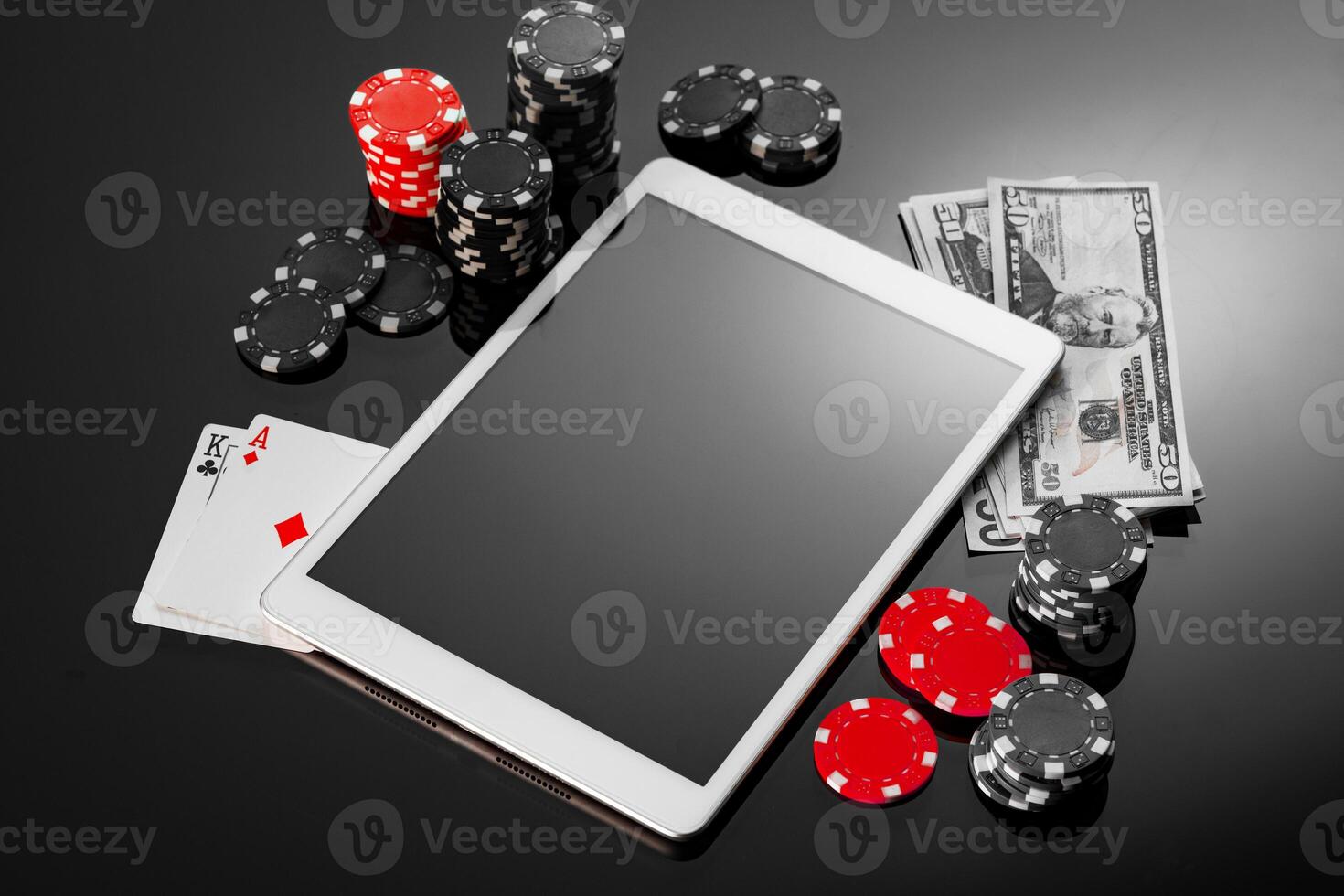 A tablet lies on a table surrounded by poker chips and playing cards in a cozy gaming lounge during the evening hours photo