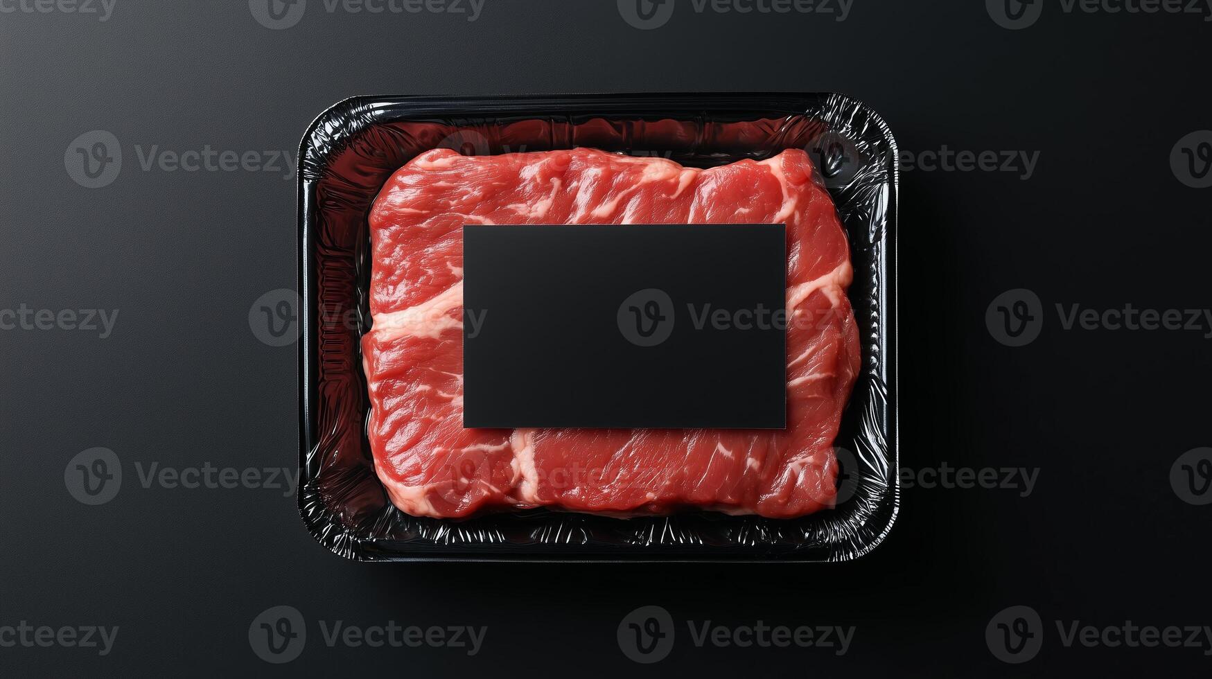 Freshly cut beef steak in a black tray with a blank label ready for seasoning and cooking preparations photo