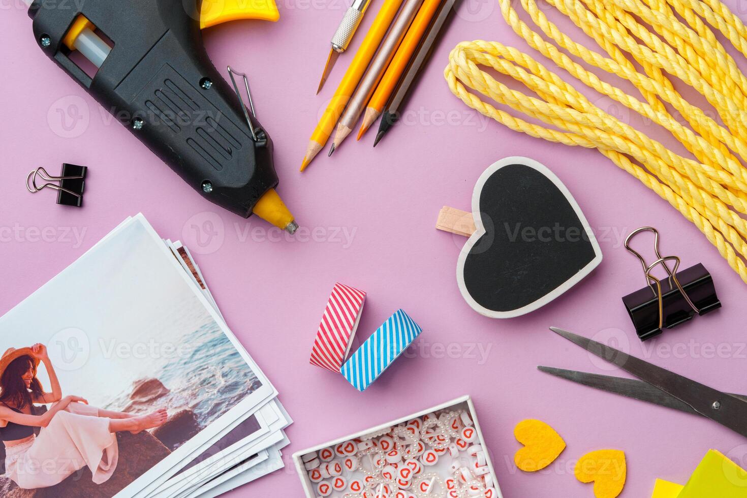 Crafting supplies arranged on a pink background, including glue gun, scissors, and decorative items for DIY projects photo