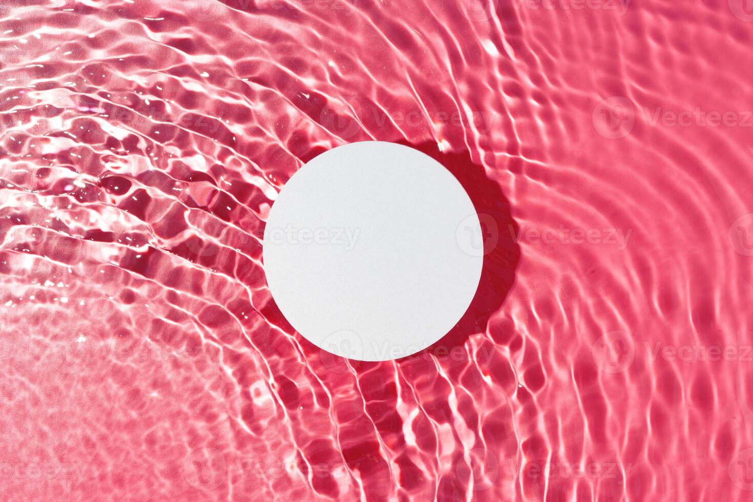 Bright circular object floating on water with pink ripples in a serene setting during daylight photo