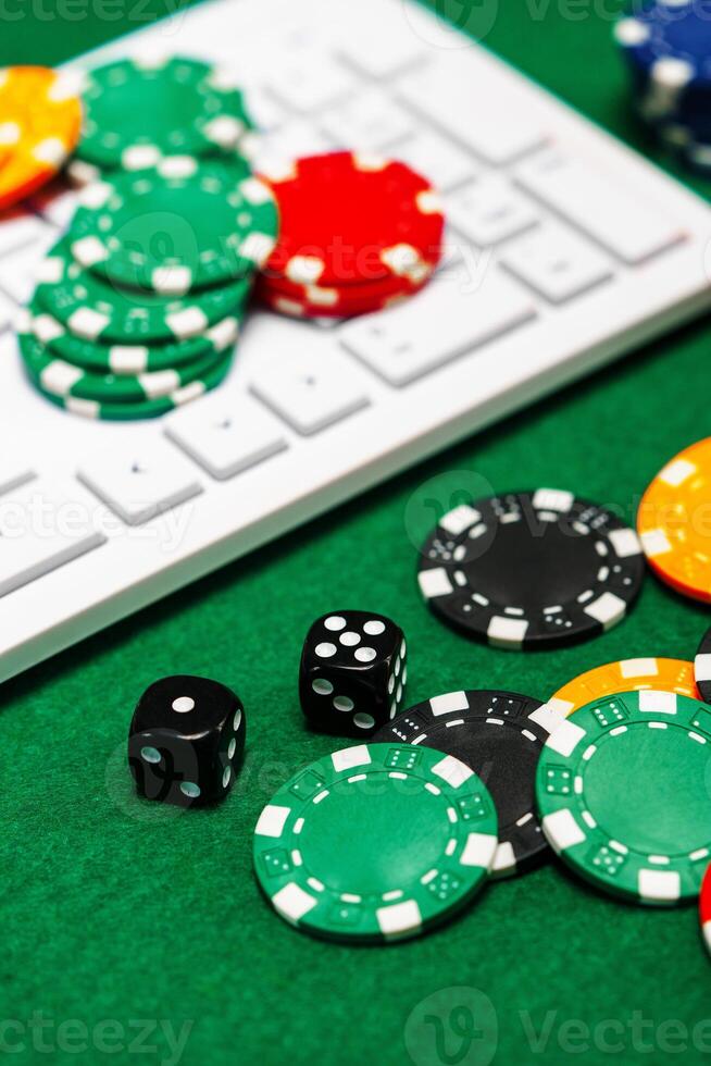 Chips and playing cards on a green felt surface near a computer keyboard during an online gaming session at home photo