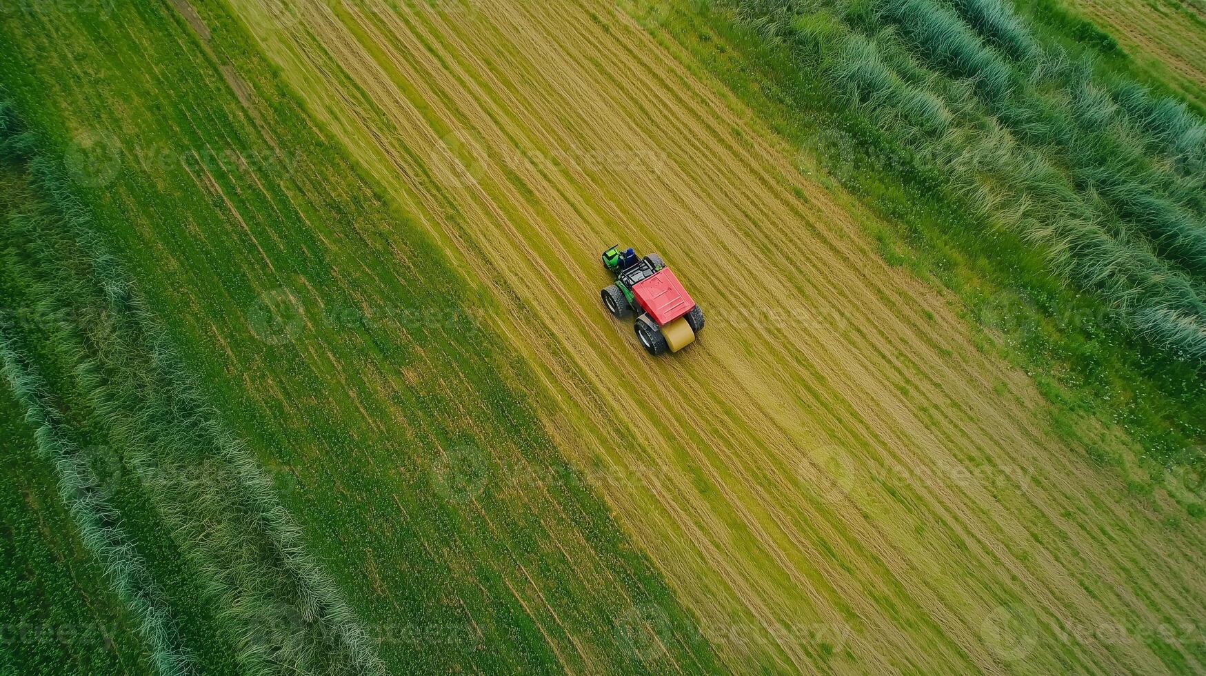 Aerial view of a red tractor working in a lush green field during the day, demonstrating modern agricultural practices photo