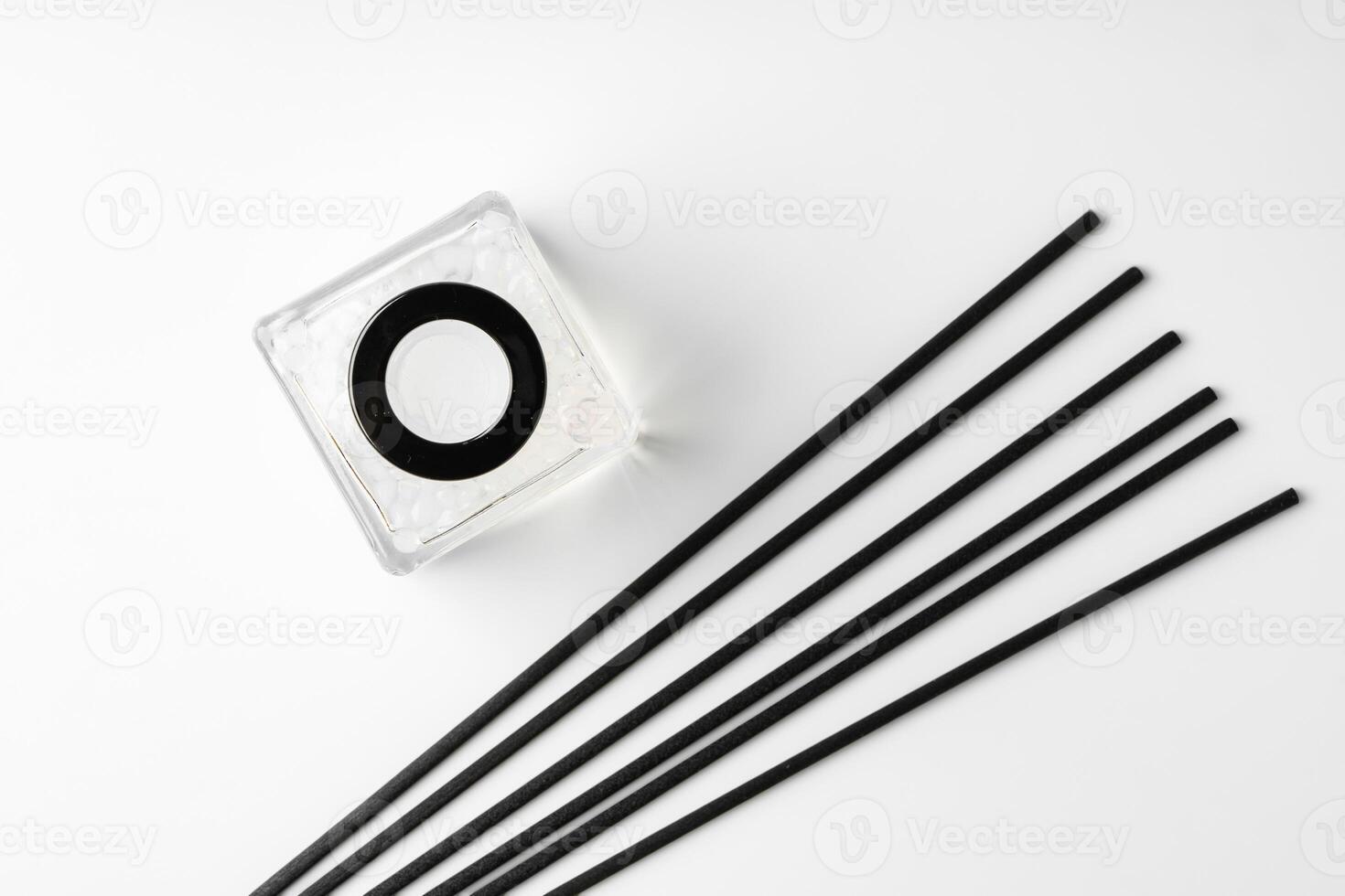 A minimalist display of essential oil and black diffuser sticks on a clean white background photo