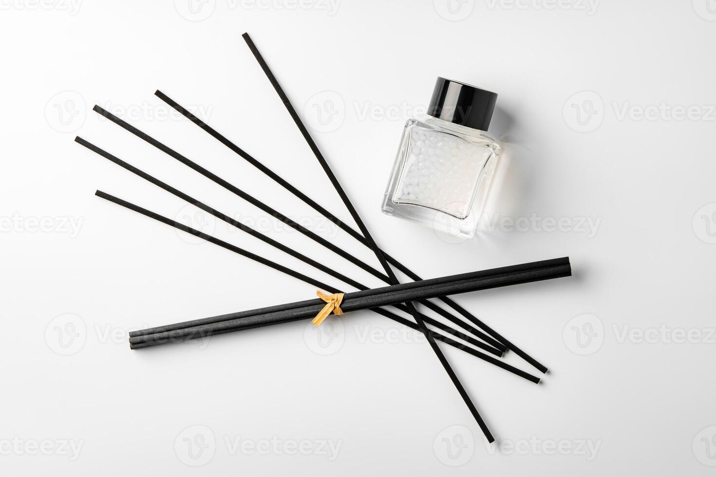 A minimalist display of essential oil and black diffuser sticks on a clean white background photo