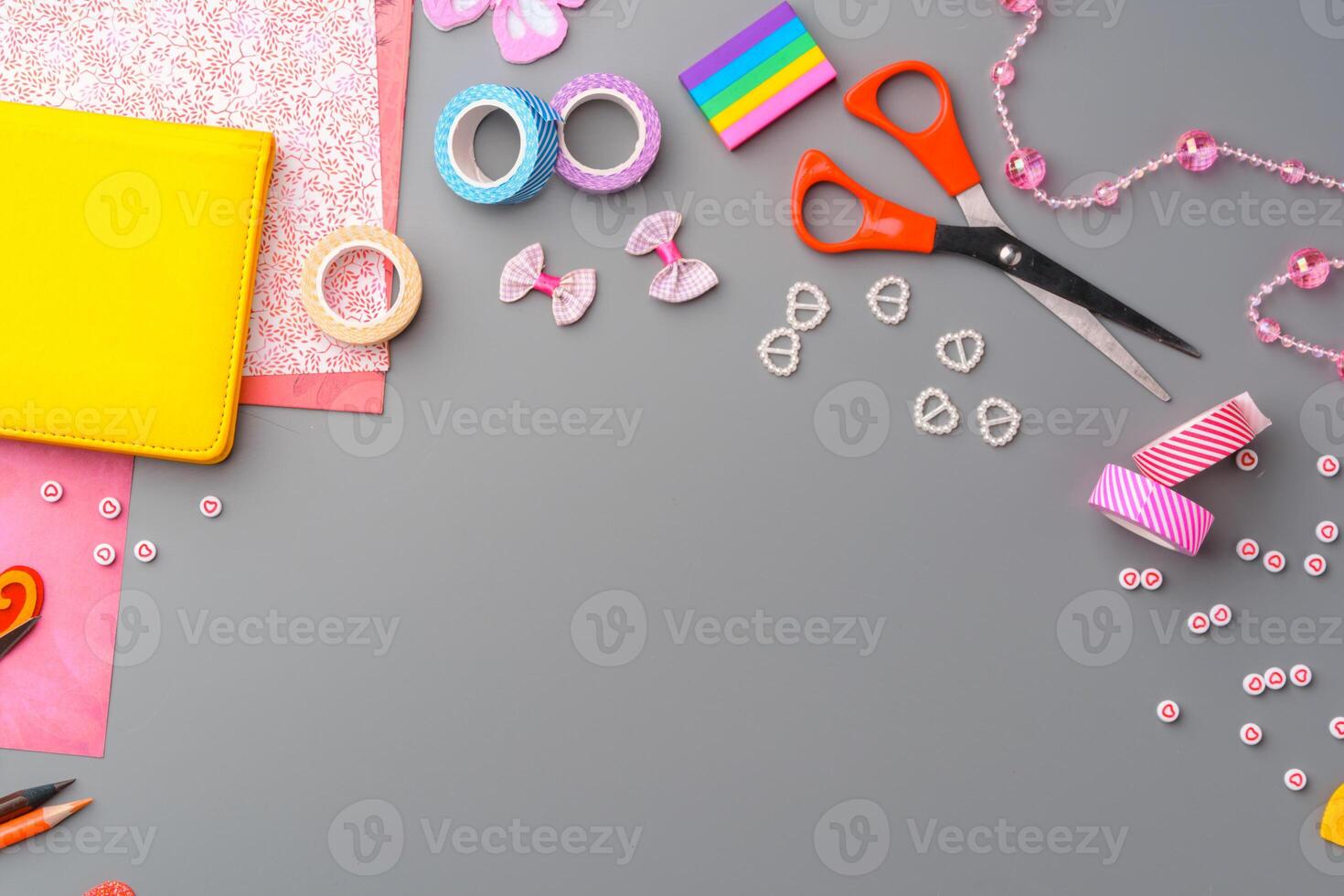 Crafting supplies arranged for a DIY project on a gray table with scissors, washi tape, and decorative items photo