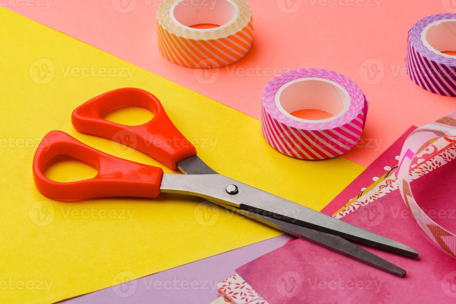 Scissors and decorative tape on colorful craft paper in a bright workspace photo