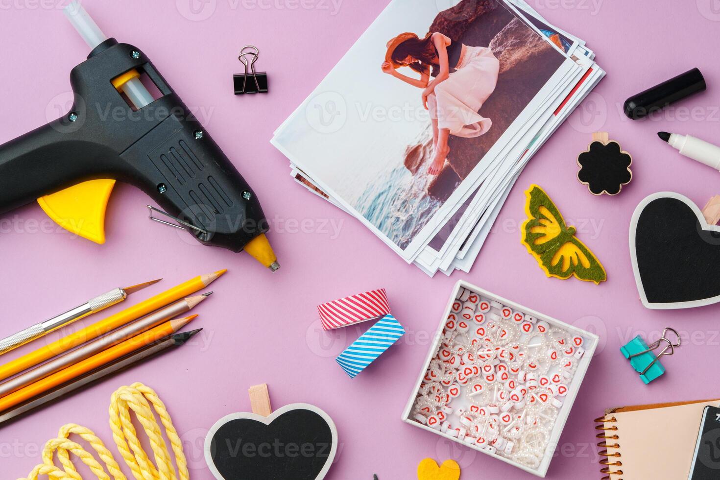 Crafting supplies arranged on a pink background, including glue gun, scissors, and decorative items for DIY projects photo