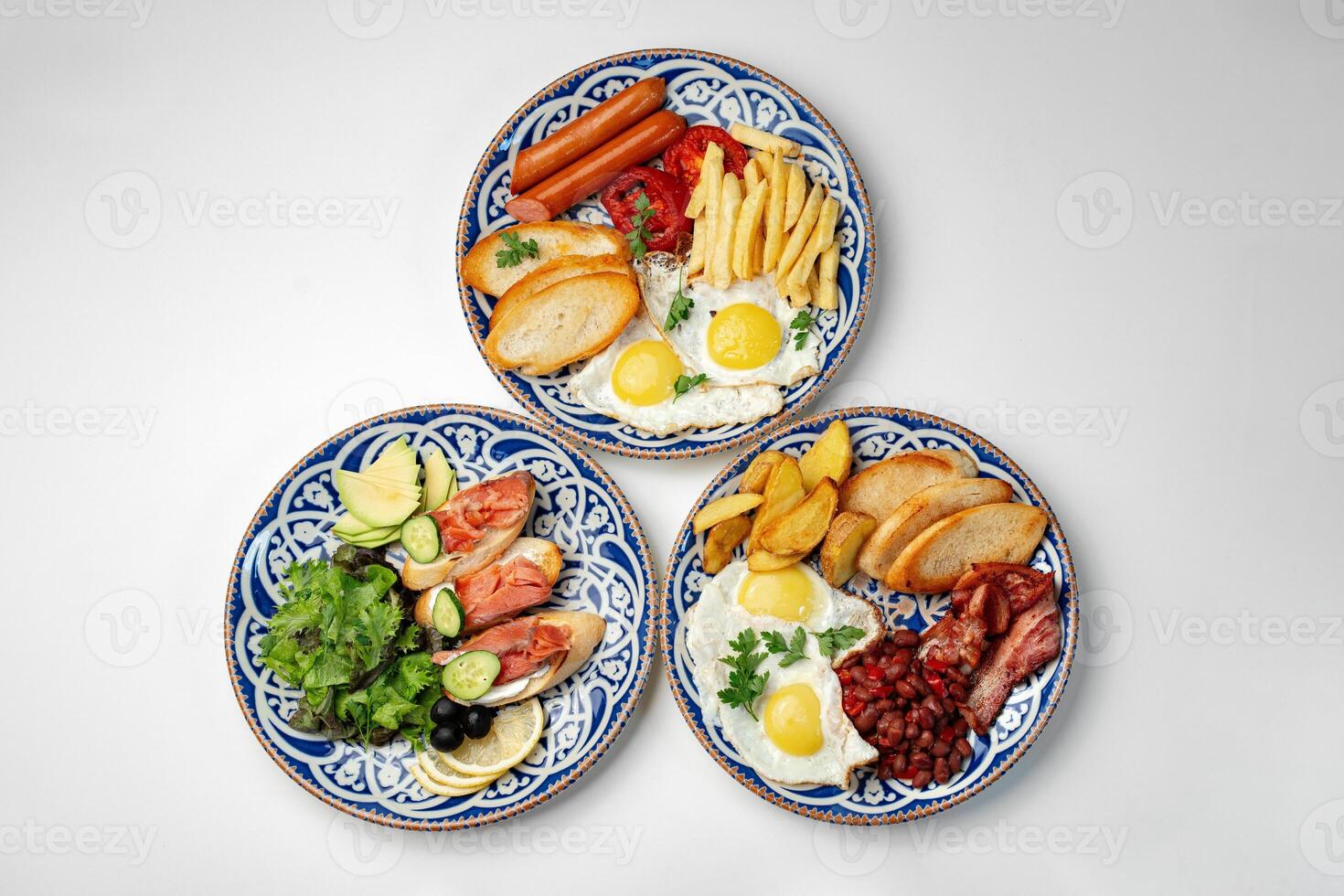 Traditional breakfast plates featuring eggs, sausages, and various accompaniments arranged artistically on a white background photo