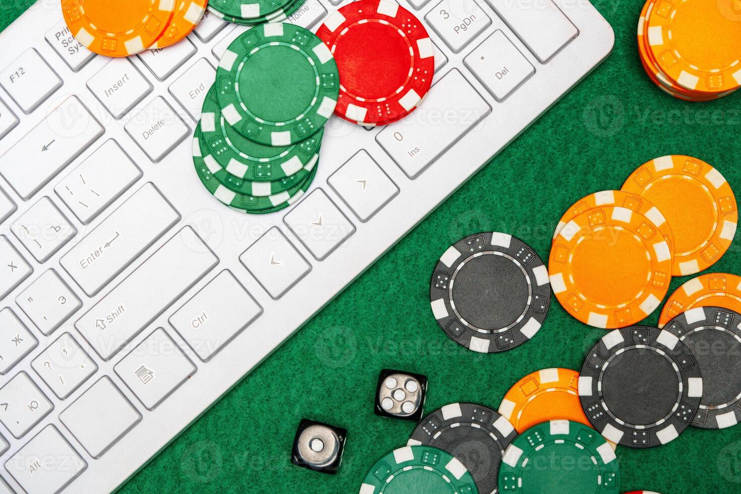 Chips and playing cards on a green felt surface near a computer keyboard during an online gaming session at home photo