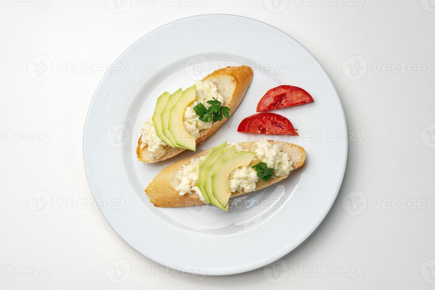 Fresh avocado and cheese spread on toasted bread garnished with cilantro and tomato photo