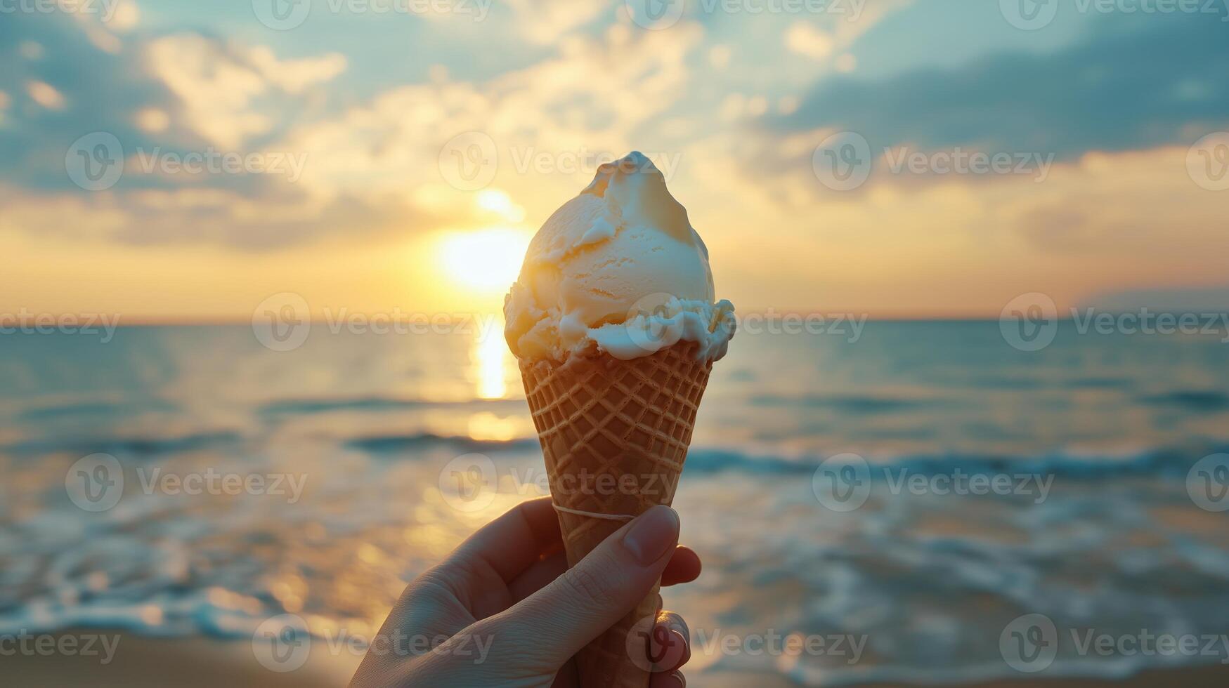 Enjoying a creamy ice cream cone by the seaside at sunset with golden hues illuminating the tranquil waves photo