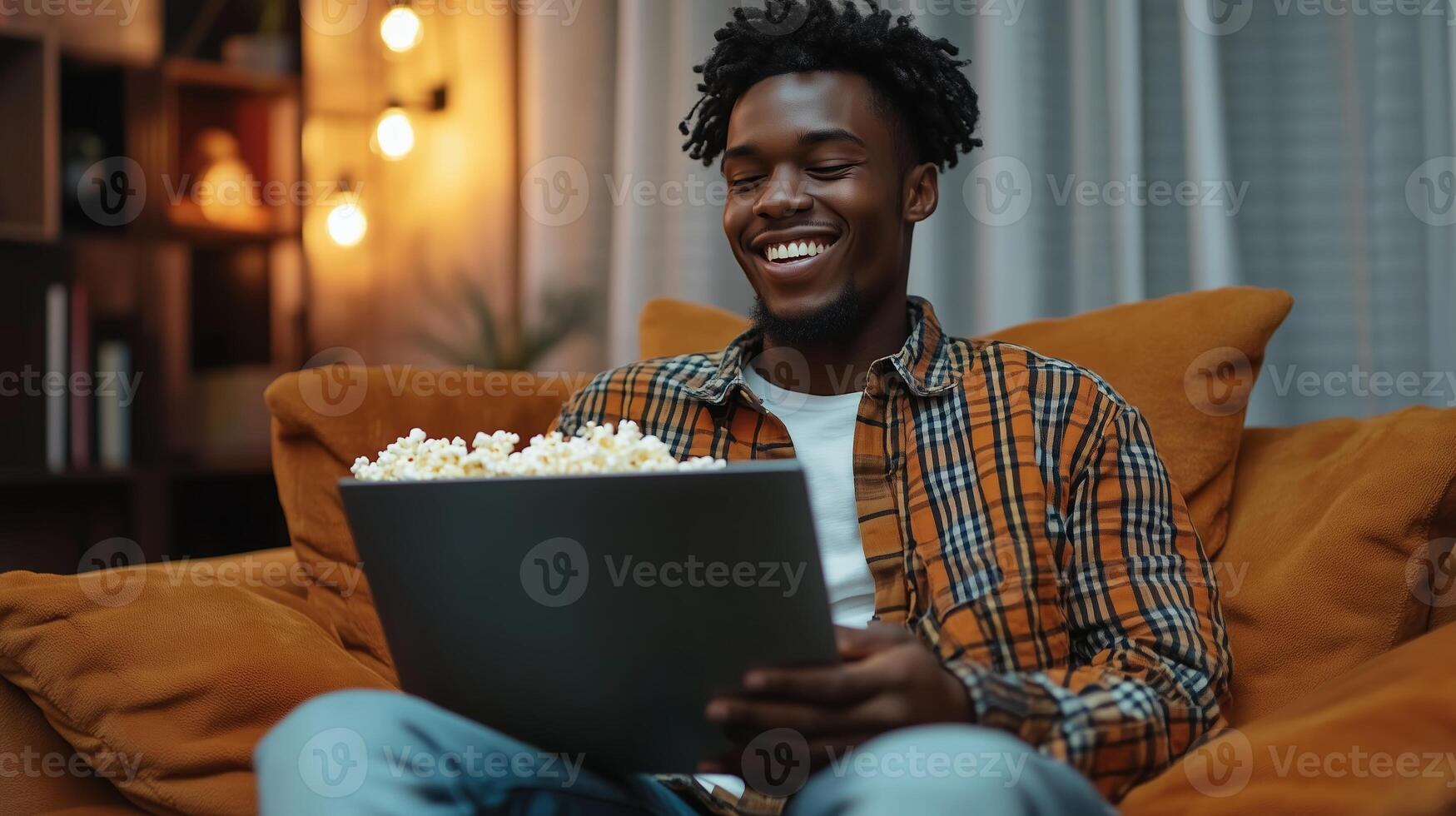 A young man enjoys a cozy movie night at home with popcorn on a comfortable couch, surrounded by warm ambient lighting photo