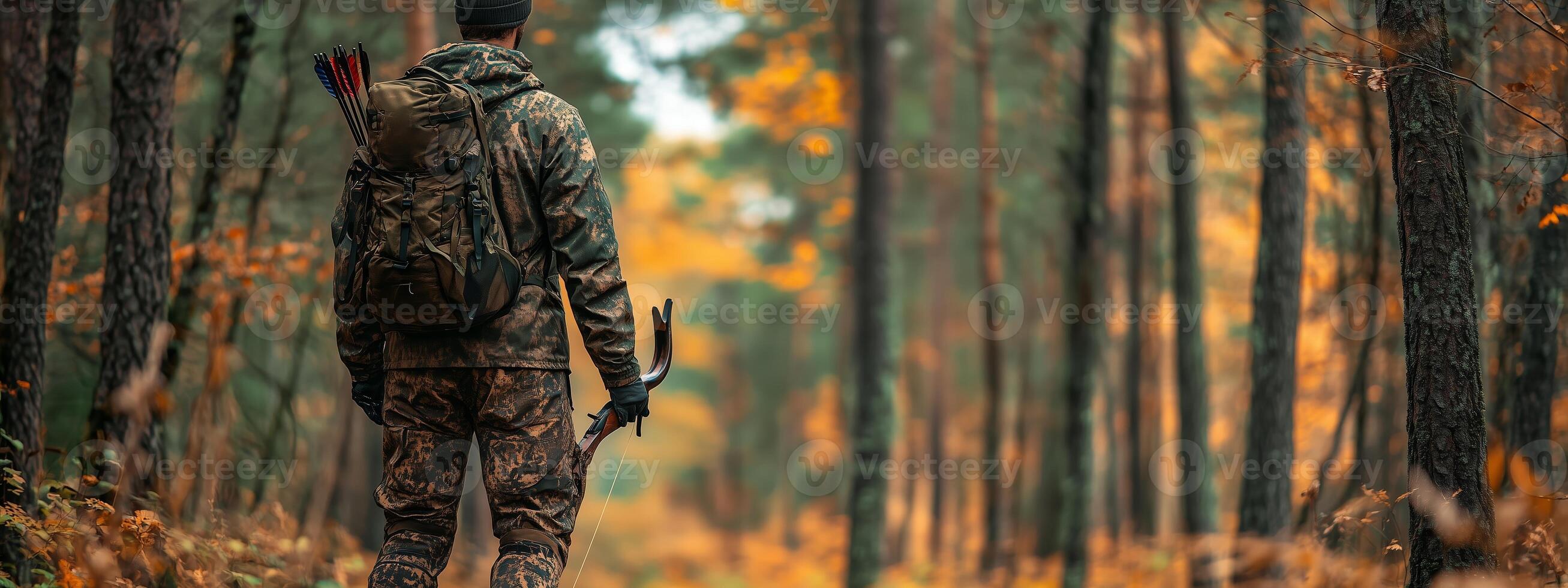 A hunter walks through an autumn forest with a bow and arrows, surrounded by colorful foliage under a cloudy sky photo