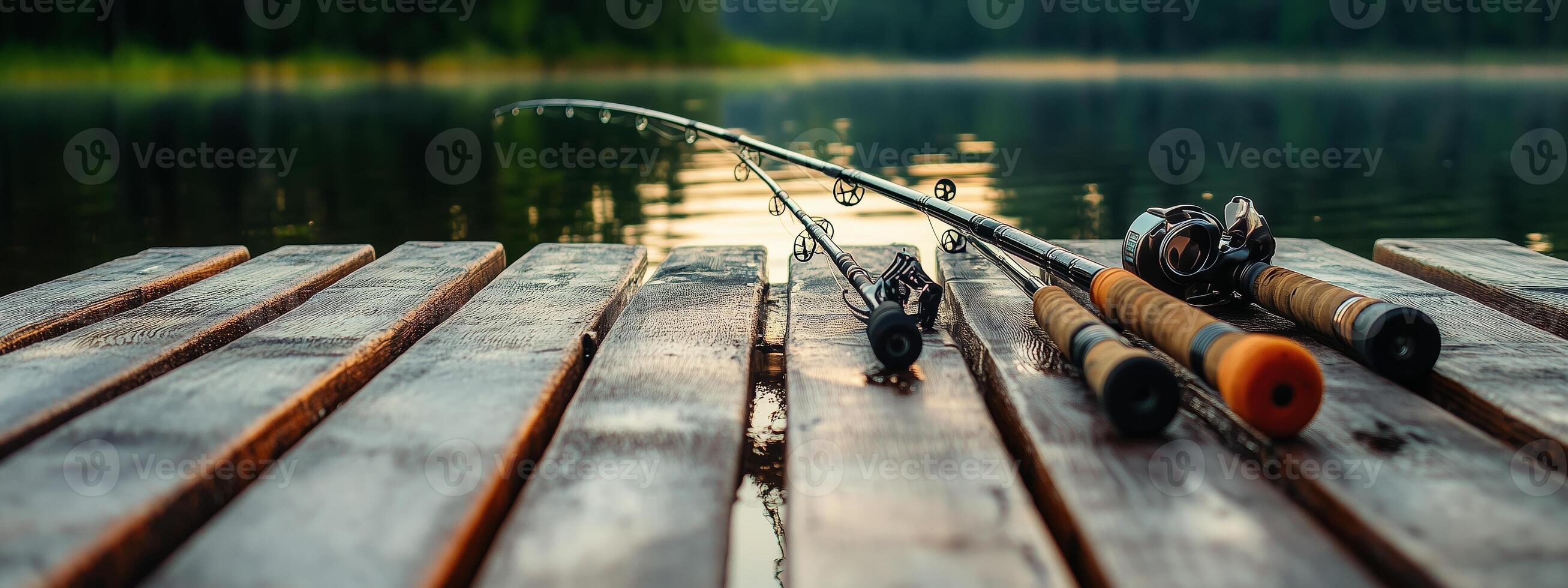 Fishing rods resting on a wooden dock at a serene lake during the early morning light reflecting off the calm water photo