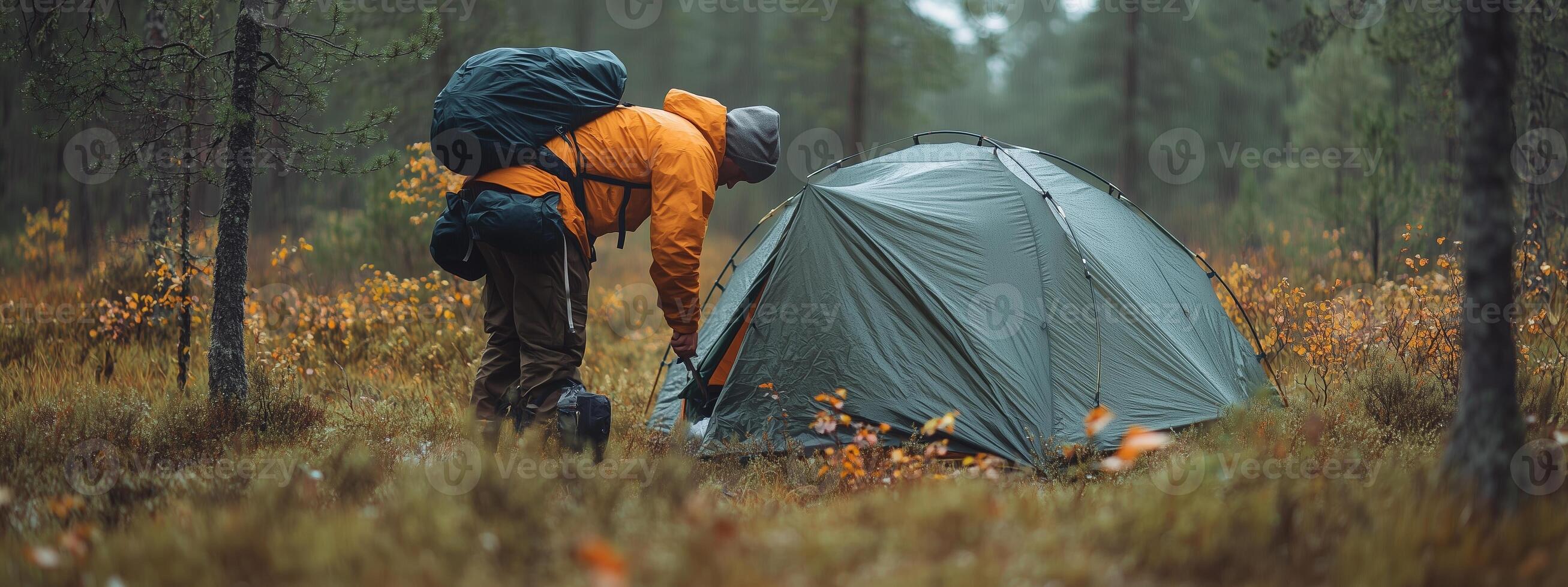 Camping enthusiast sets up a tent in the tranquil forest during autumn, surrounded by colorful foliage and soft morning light photo