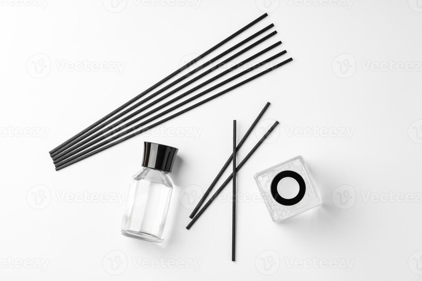 A minimalist display of essential oil and black diffuser sticks on a clean white background photo