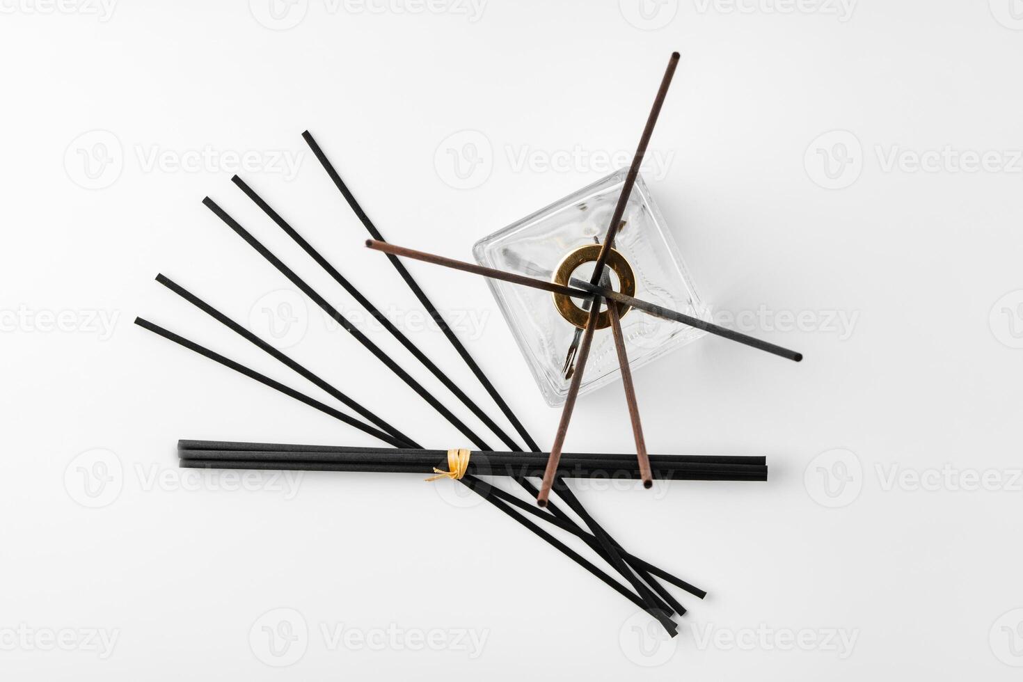 A minimalist display of essential oil and black diffuser sticks on a clean white background photo