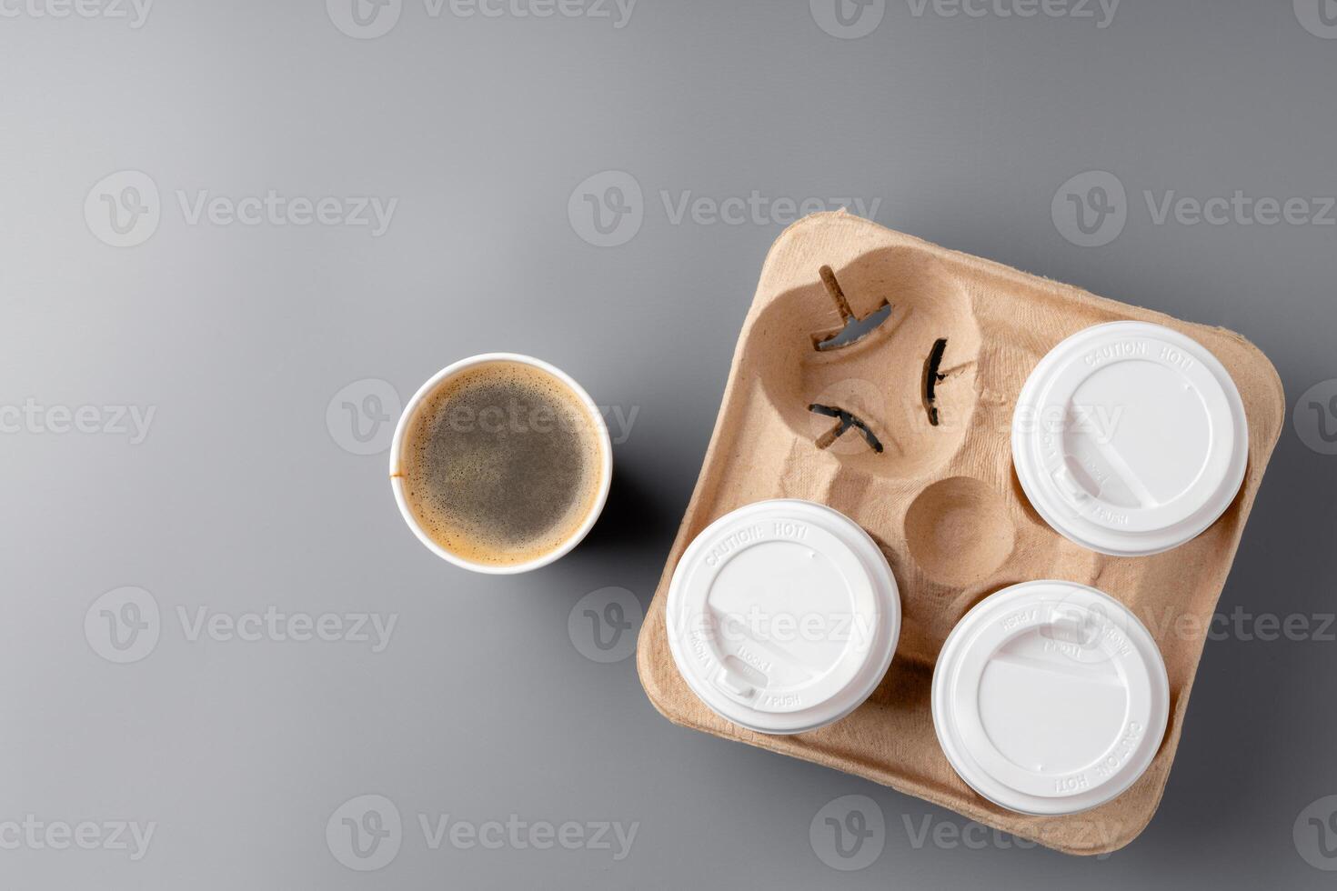 Warm coffee in a brown paper cup on a gray surface with a tray photo