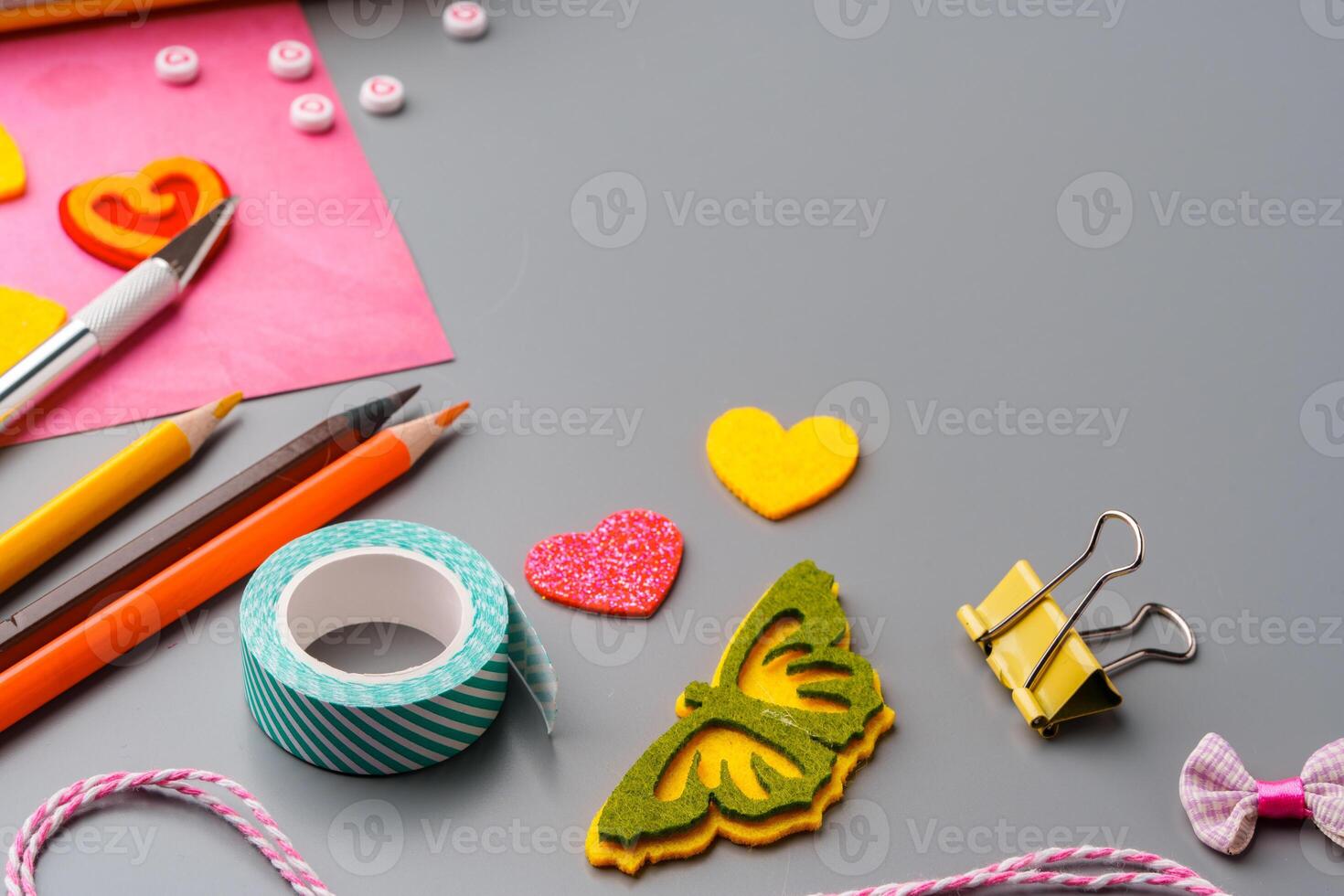 Crafting supplies arranged for a DIY project on a gray table with scissors, washi tape, and decorative items photo