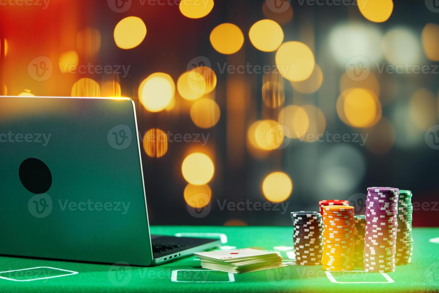 A laptop and poker chips arranged on a green felt table in an indoor gaming setup during a nighttime gambling session photo