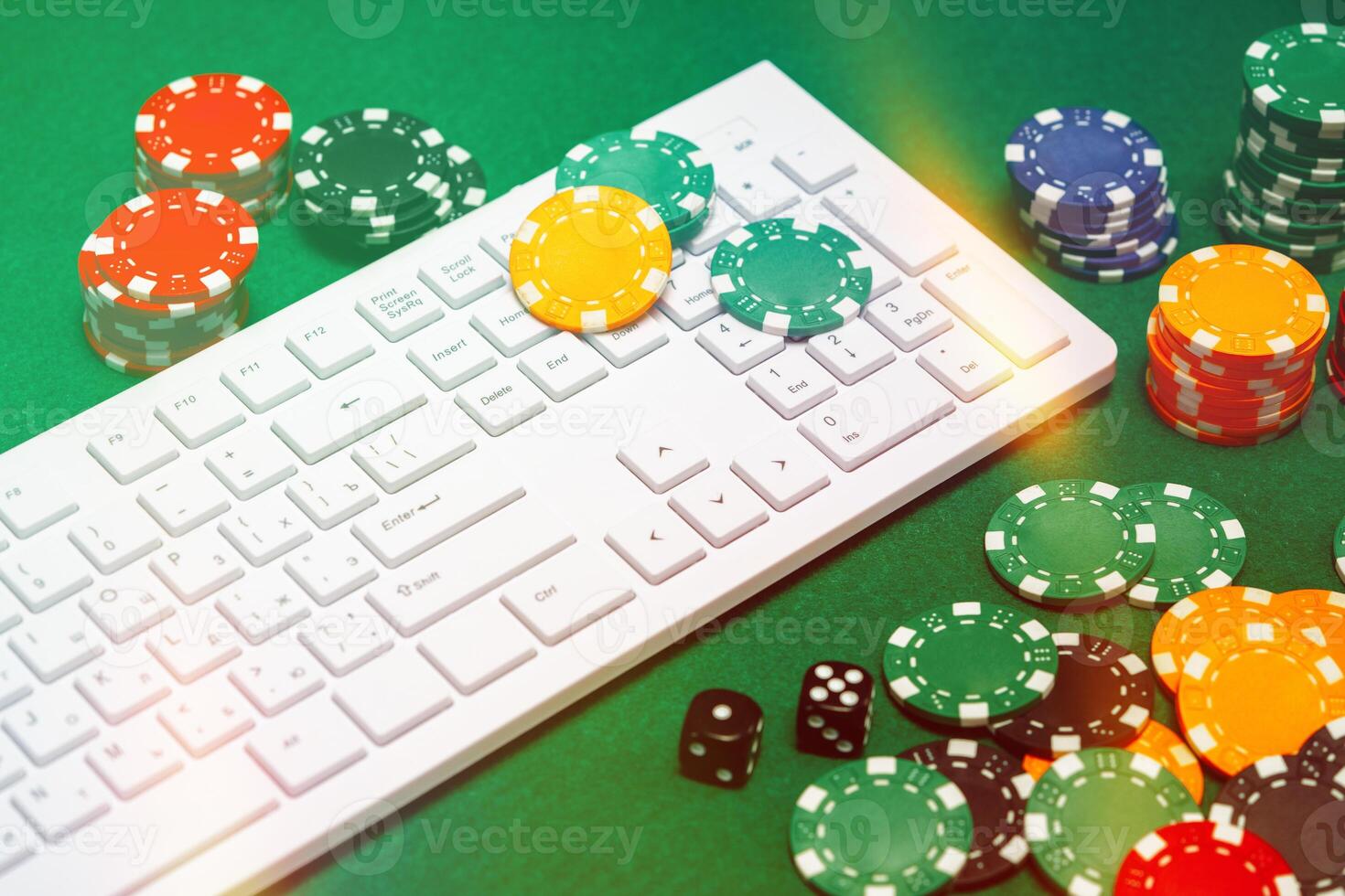 Chips and playing cards on a green felt surface near a computer keyboard during an online gaming session at home photo